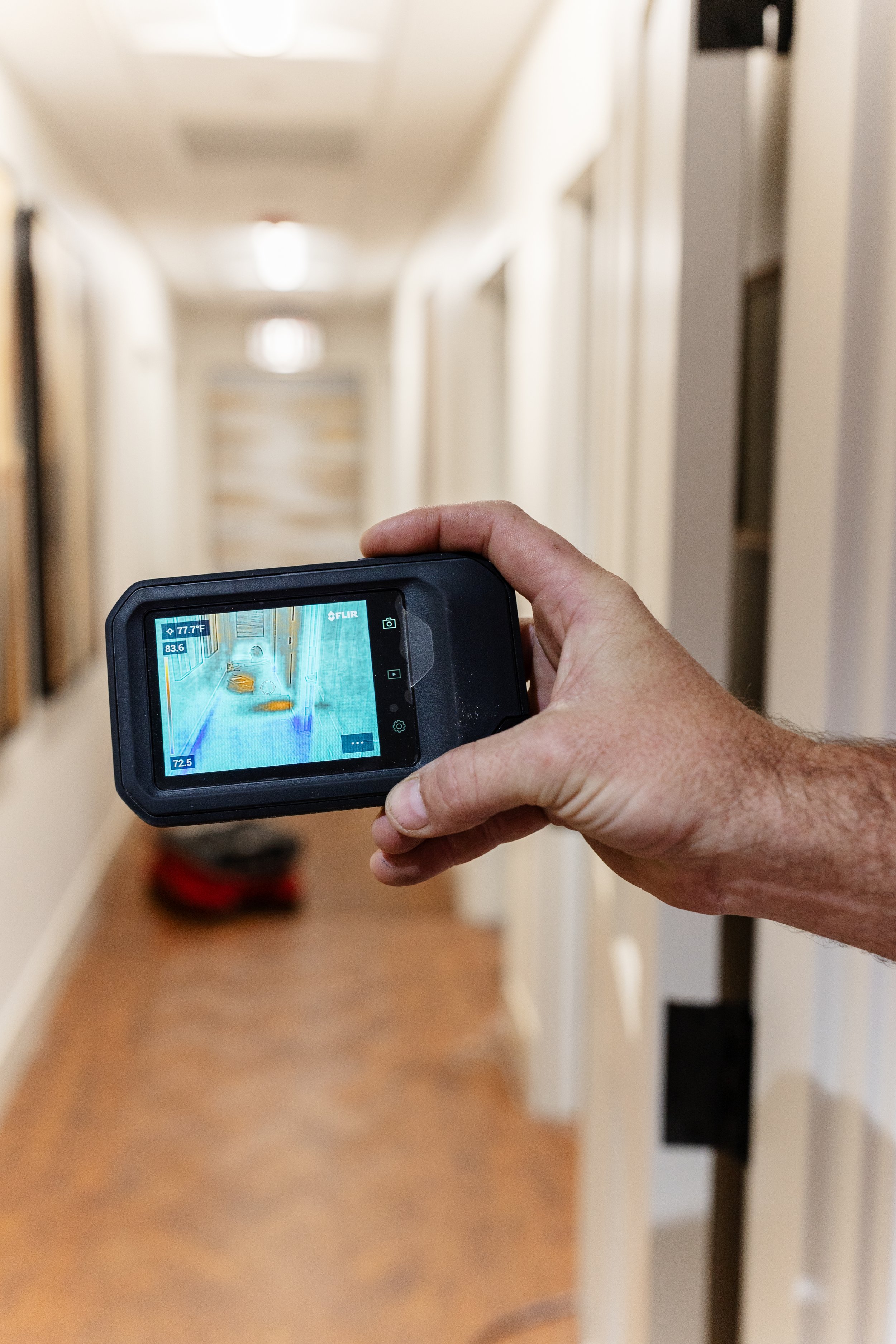 Person using a thermal imaging camera to scan a hallway.