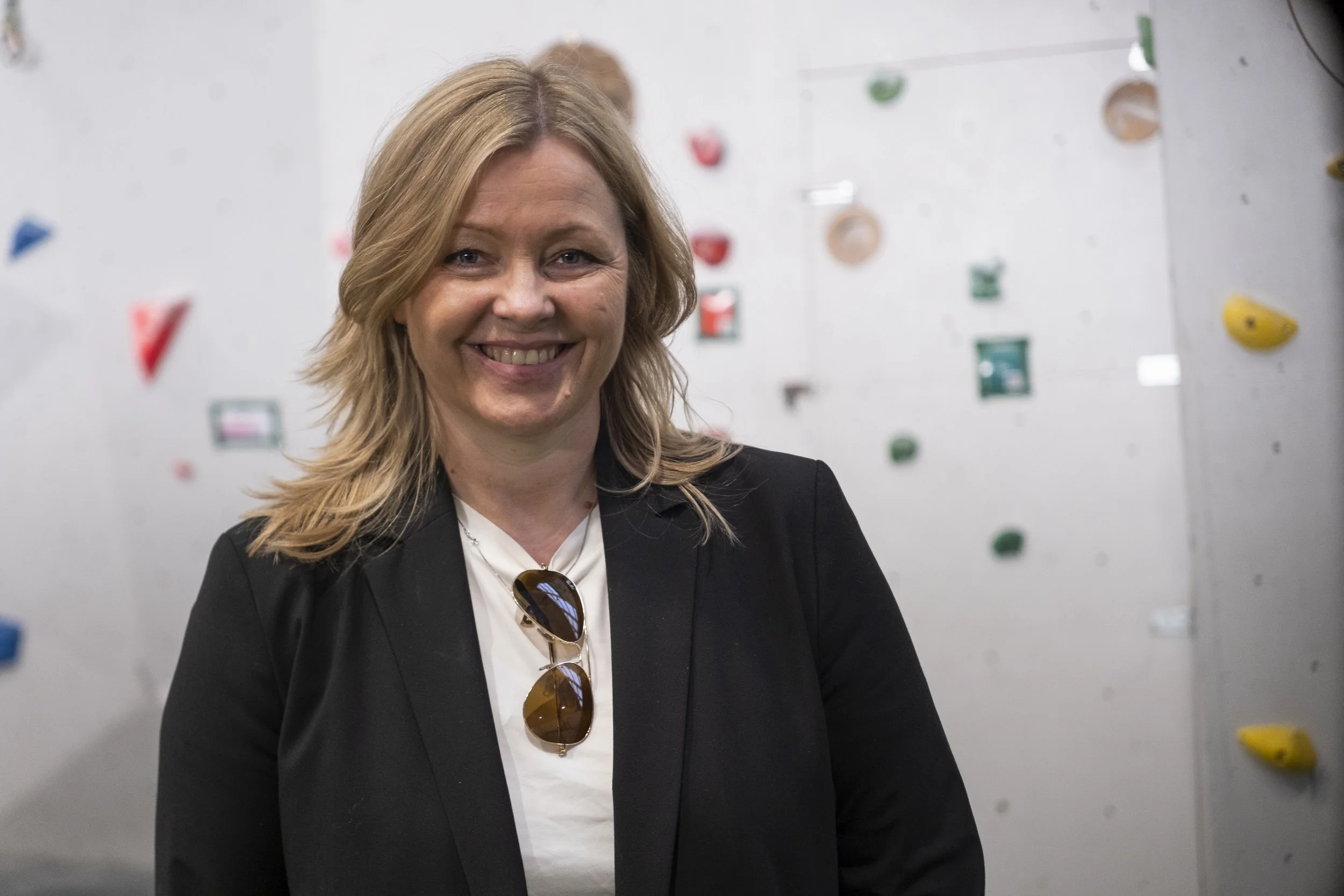 Kommunal- og distriktsminister
Kjersti Stenseng (Ap) med blond hår og mørk blazer, står foran en innendørs klatrevegg med fargerike håndtak. Foto: Benjamin Haug-Toklum