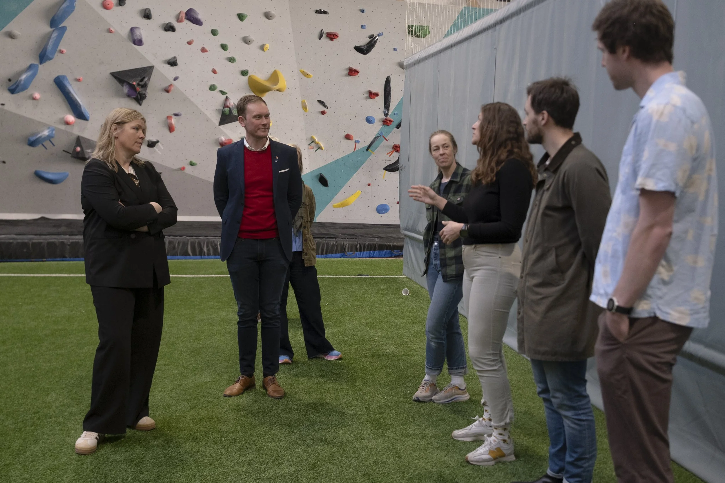 En gruppe mennesker står i en innendørs klatrehall, med en kunstig klatrevegg i bakgrunnen. Kommunal- og distriktsminister
Kjersti Stenseng (Ap) snakker med en gjeng folk. Foto: Benjamin Haug-Toklum