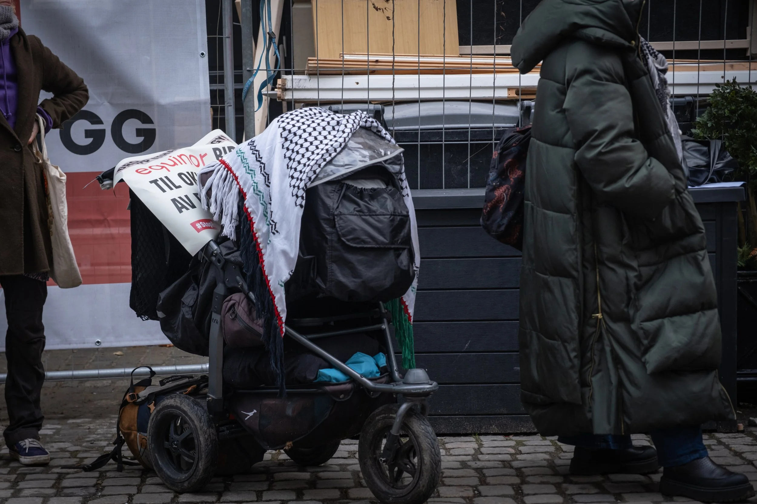 Personer står ved en bod, en av dem har en barnevogn med skjerf over, en annen person har en lang, grønn jakke. Foto: Benjamin Haug-Toklum