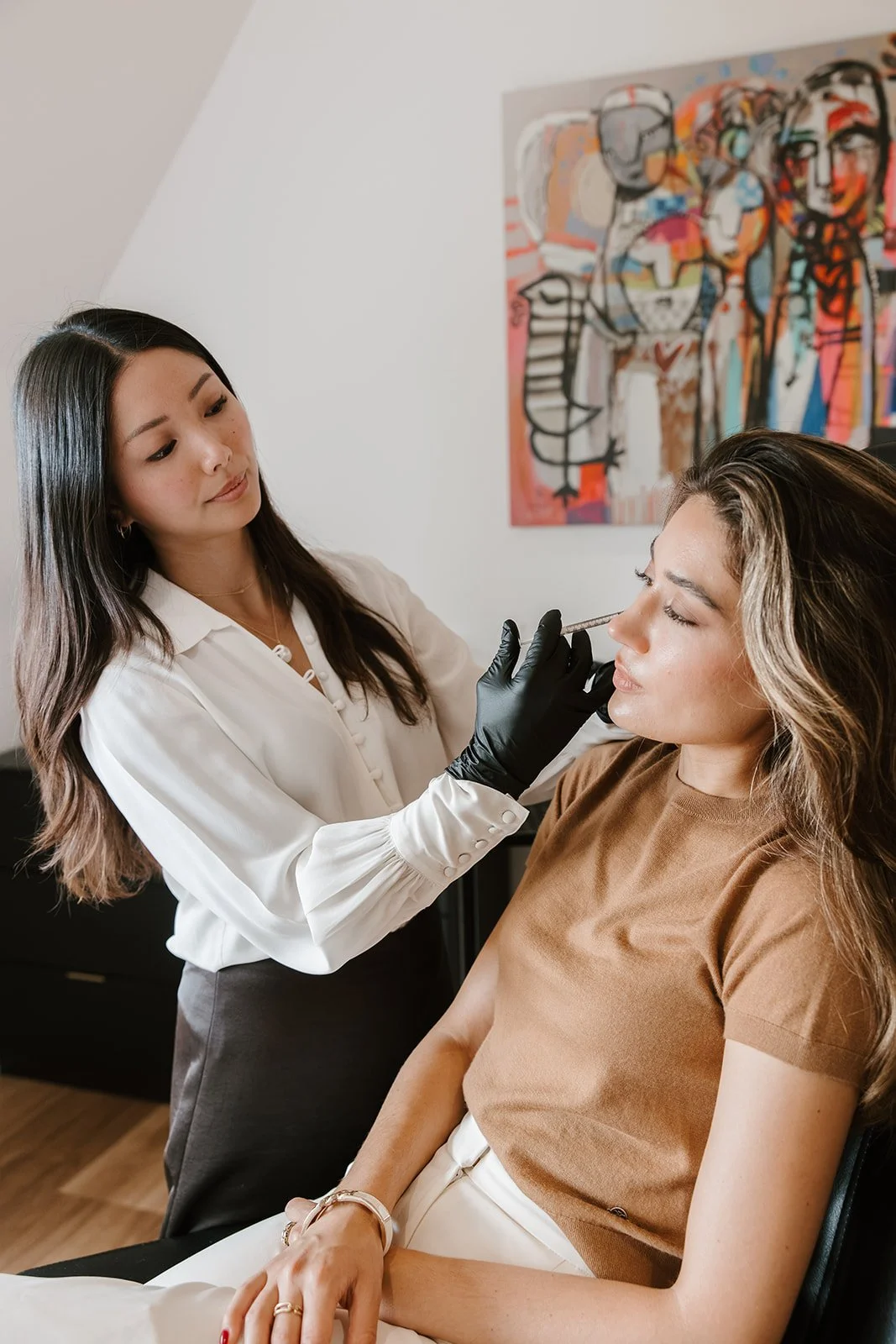 A woman receiving a cosmetic treatment on her nose from a professional in a clinical setting.
