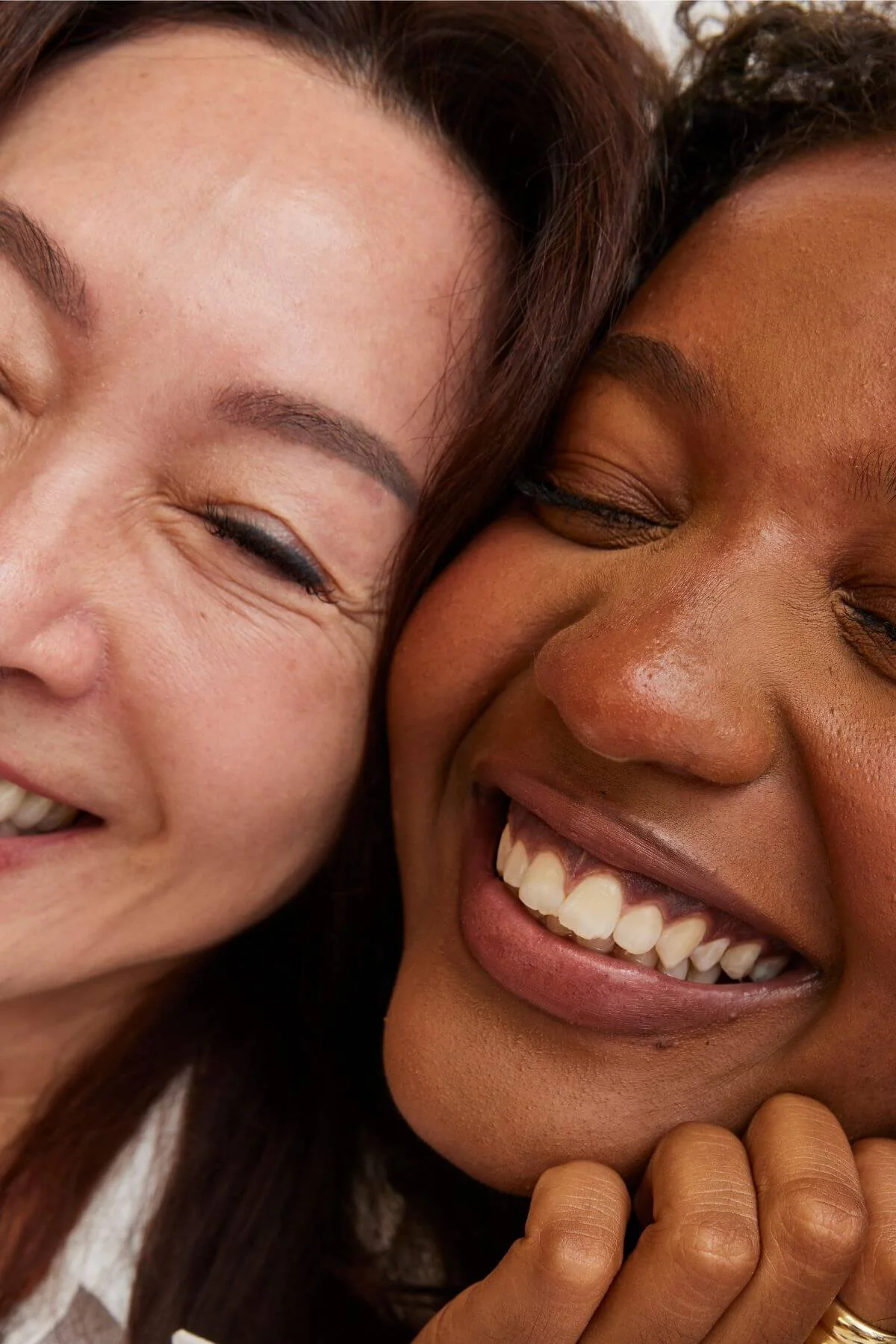 Close-up of two women smiling and laughing, showing their faces and expressions of joy.