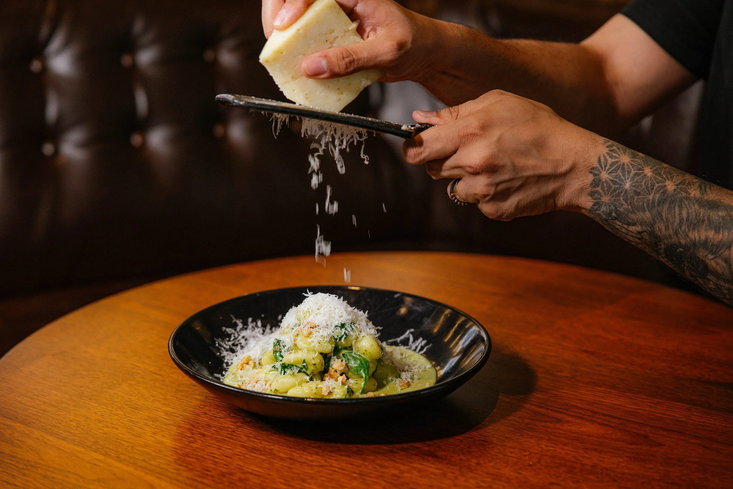 A plate of gnocchi with cheese being grated over it.