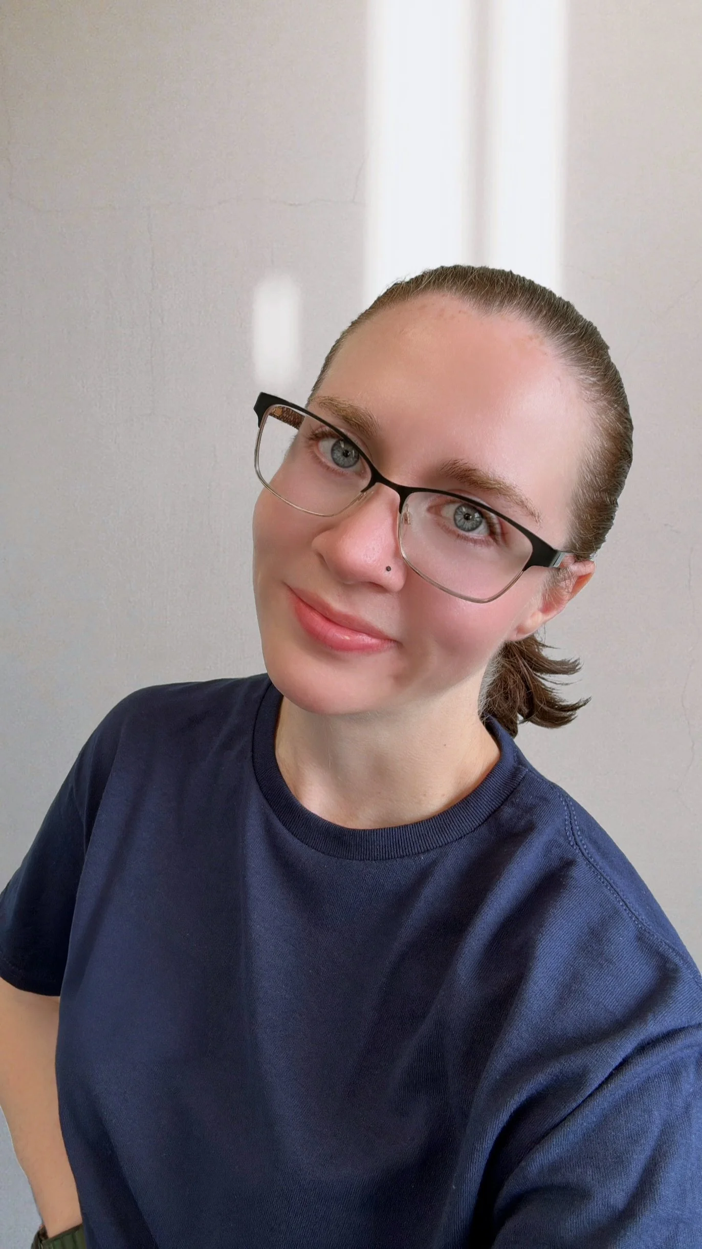 A woman with dark hair tied back, wearing glasses with tinted lenses and a gray t-shirt with a graphic of an airplane and the words "Pacific Aviation Solutions".