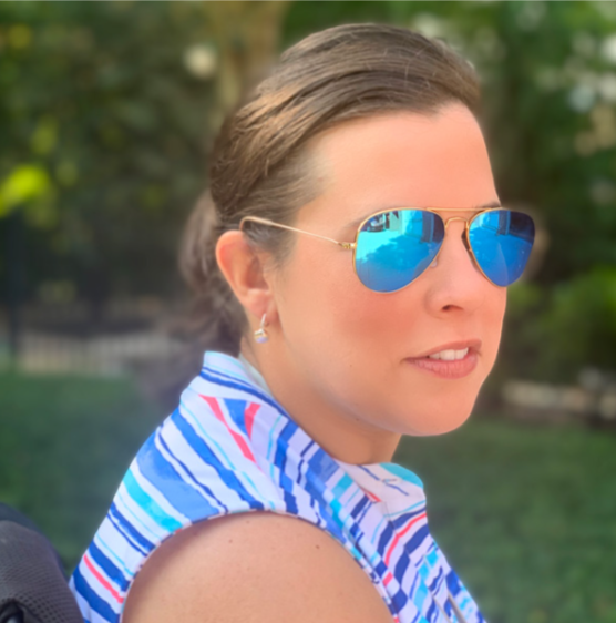 A woman wearing blue mirrored sunglasses and a blue and white striped sleeveless top outdoors.