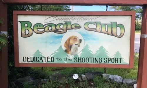 Sign for the Amite County Beagle Club dedicated to shooting sport, with an illustration of a beagle and pine trees in the background.