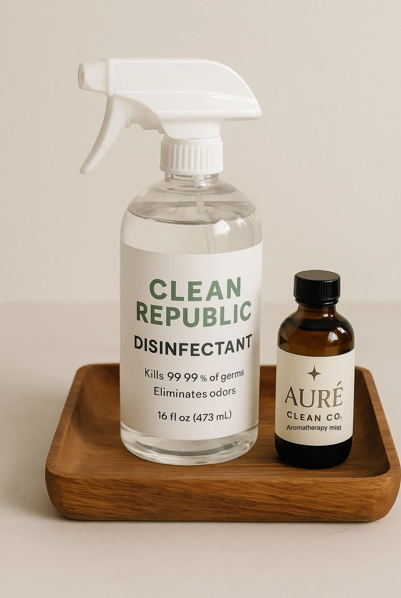 A wooden tray holds a clear spray bottle labeled "Clean Republic Disinfectant" and a small brown bottle labeled "Auré Clean Co Aromatherapy mist."