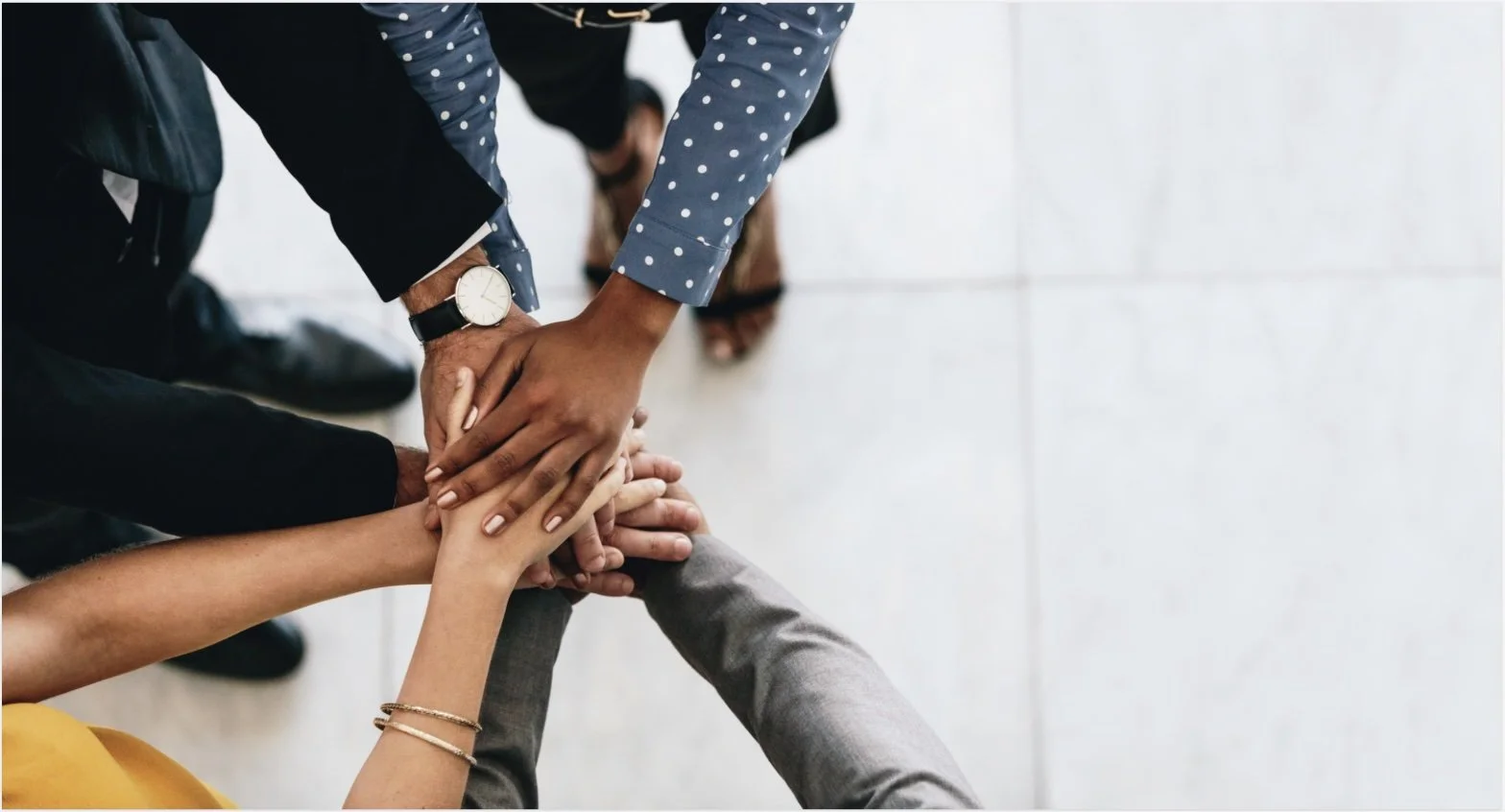 Multiple people are stacking their hands together in a gesture of teamwork or unity, viewed from above.