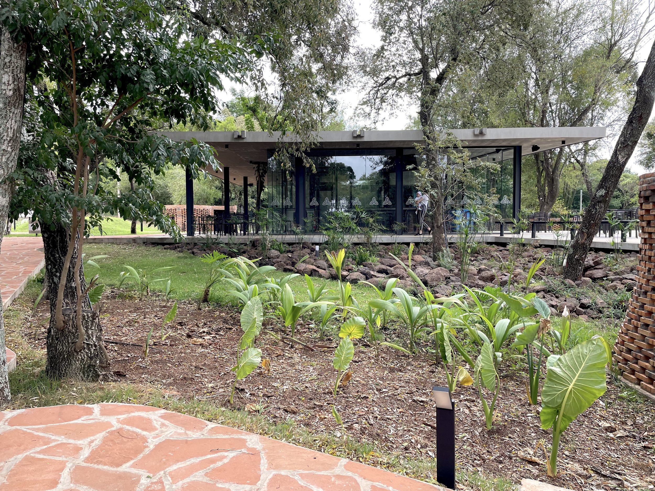 ARQUITECTAVA Vista aérea de un paisaje rural con áreas verdes, casas, caminos y un parque con piscina en el centro.