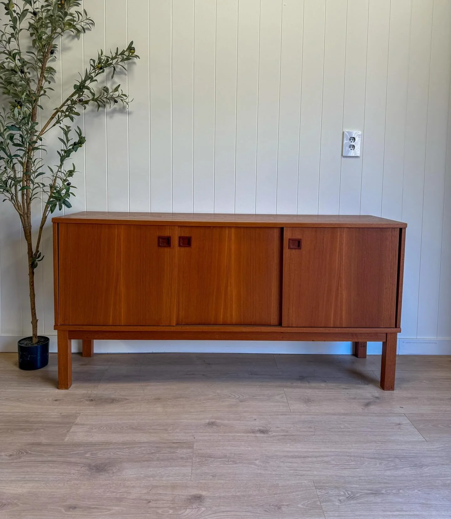 MCM mid century Danish Modern vintage teak credenza/sideboard/tv stand. Circa 1960&rsquo;s/1970&rsquo;s. This credenza features beautiful teak wood grains, solid square teak legs, and 3 sliding doors that expose shelving behind. All doors slide smoot