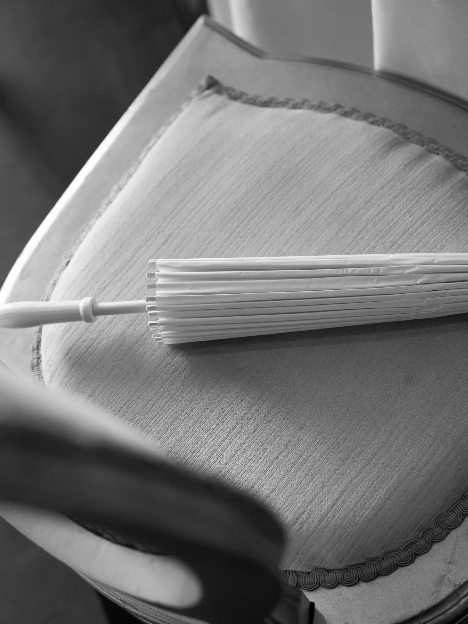 Close-up of a white cake with decorative border, topped with a bundle of straws, on a table.