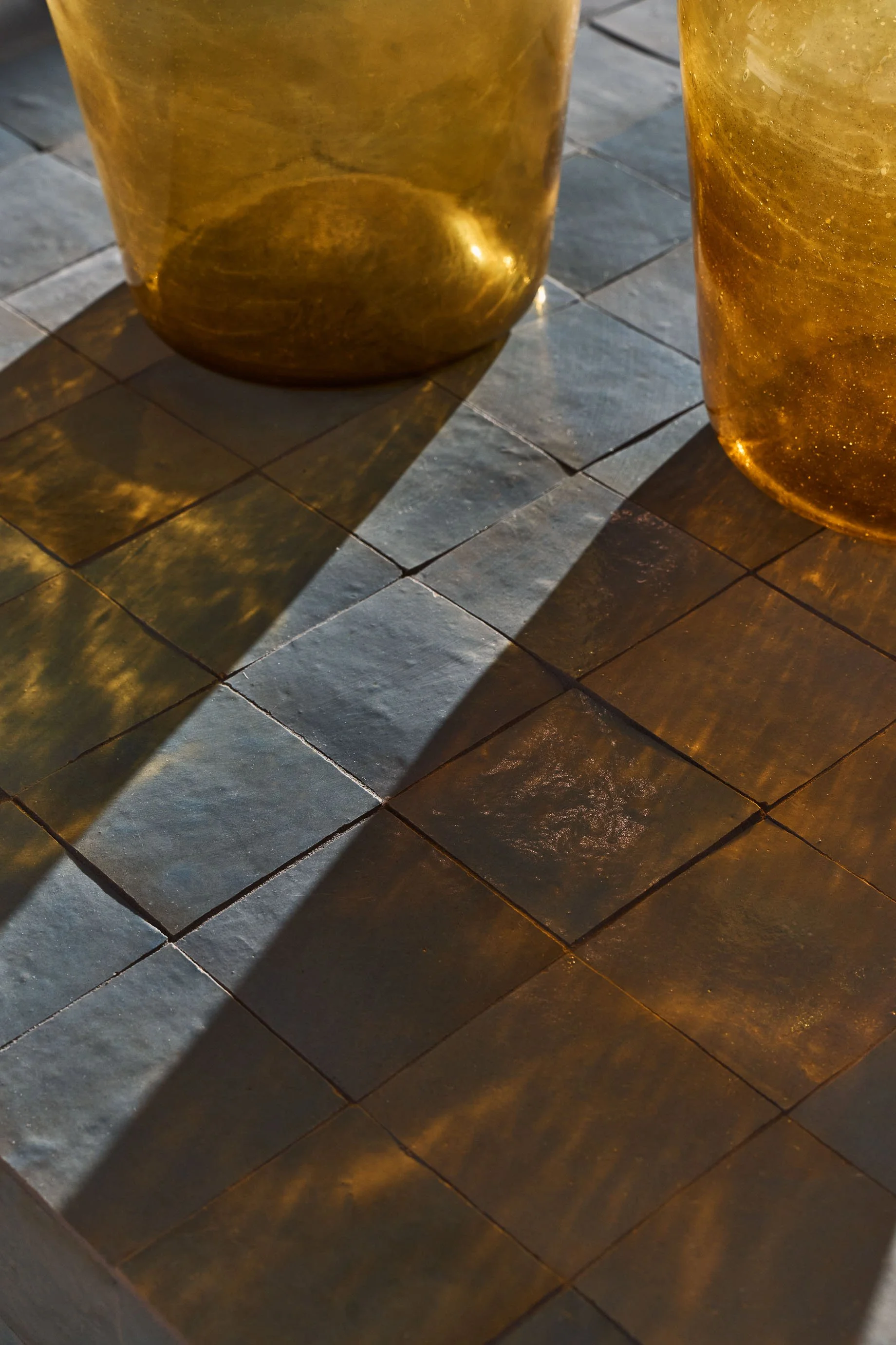Close-up of handmade grey and brown floor tiles in sunlight