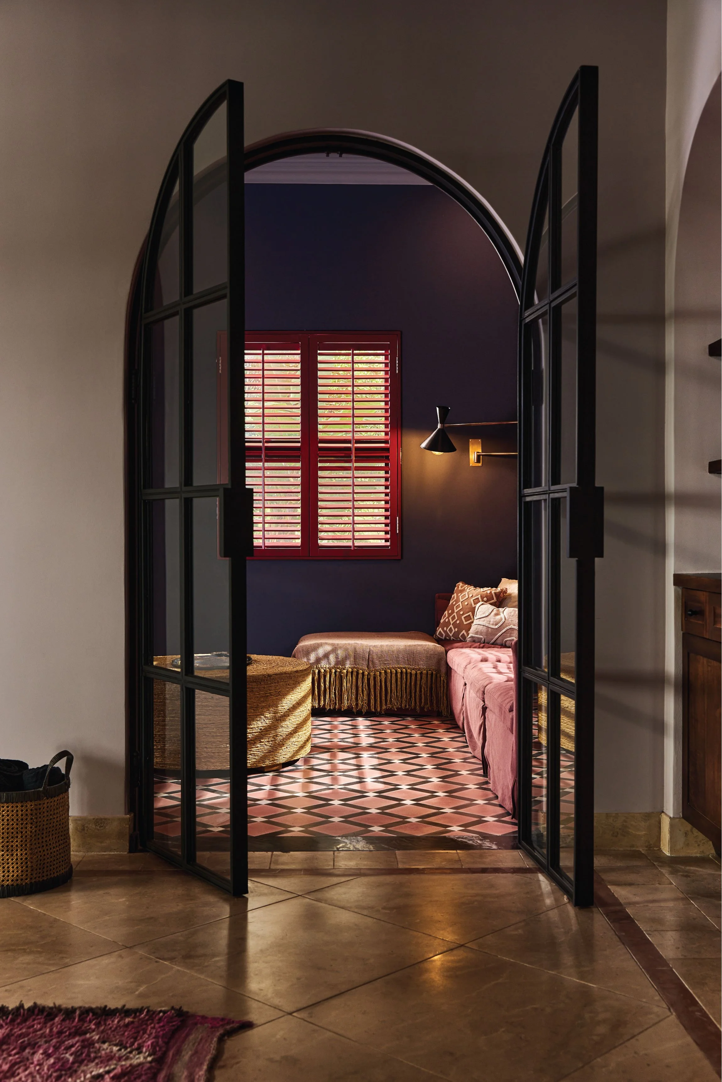 Steel-framed glass doors opening onto a navy den with a red shuttered window, Casa Ladera