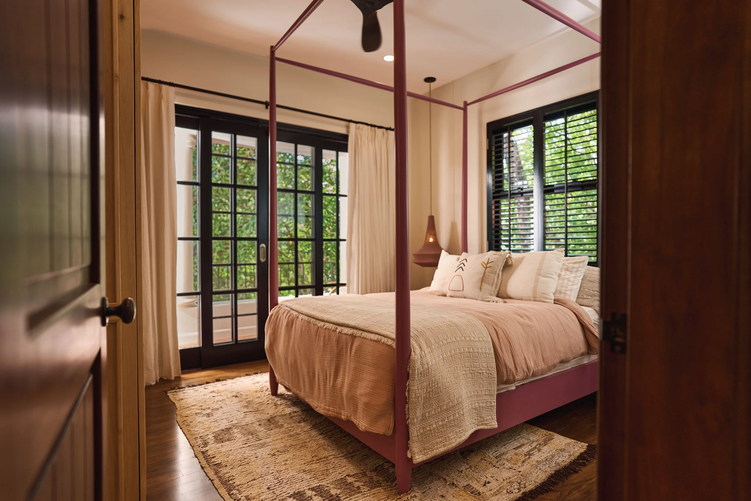 Casa Ladera bedroom with a four-poster wood bed and black-framed windows