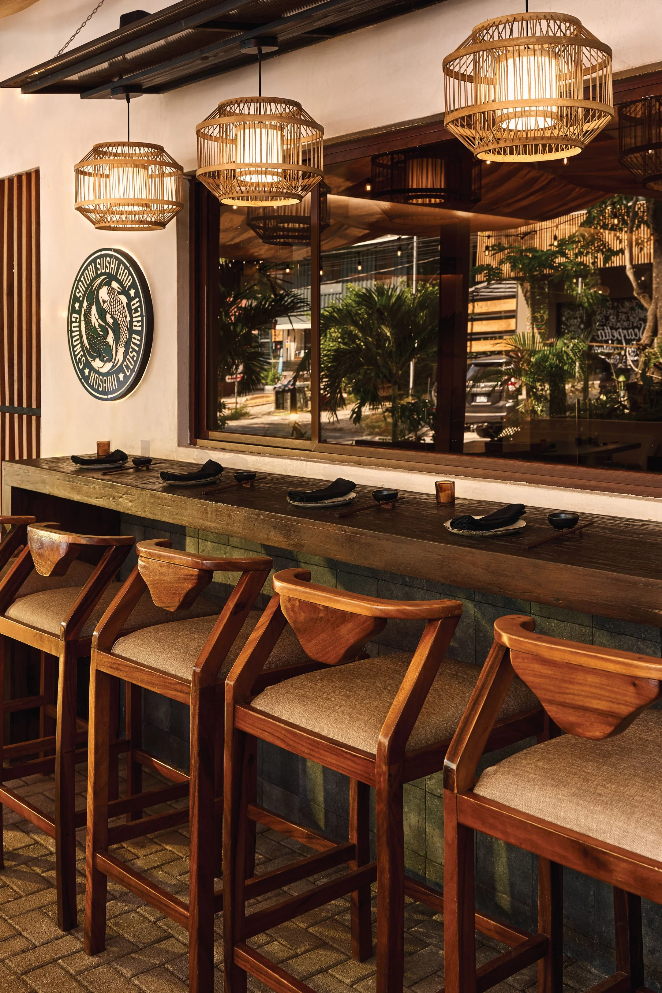 Window counter with carved wooden stools and black place settings, Satori