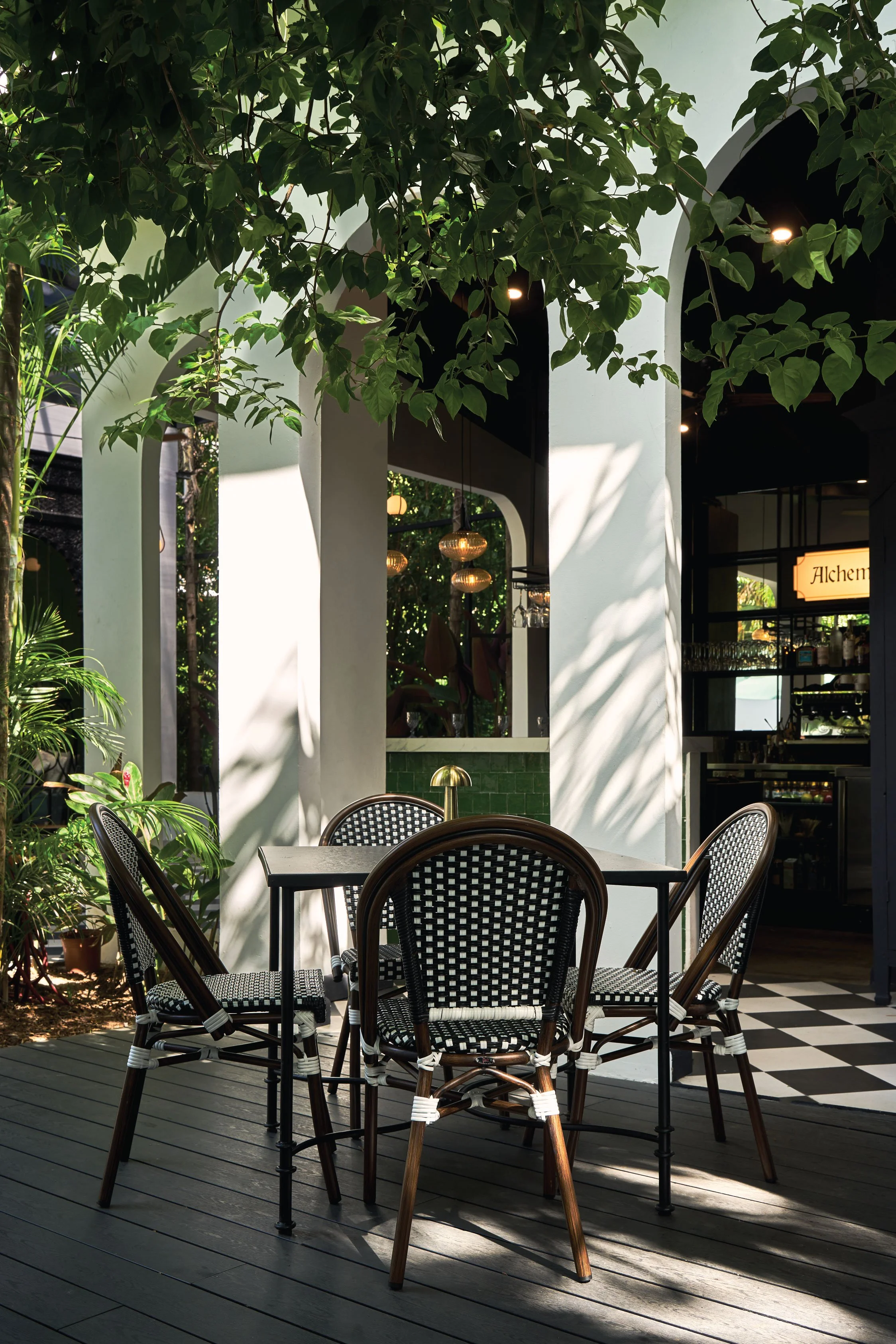 Outdoor café with bistro chairs between white columns and tropical plants