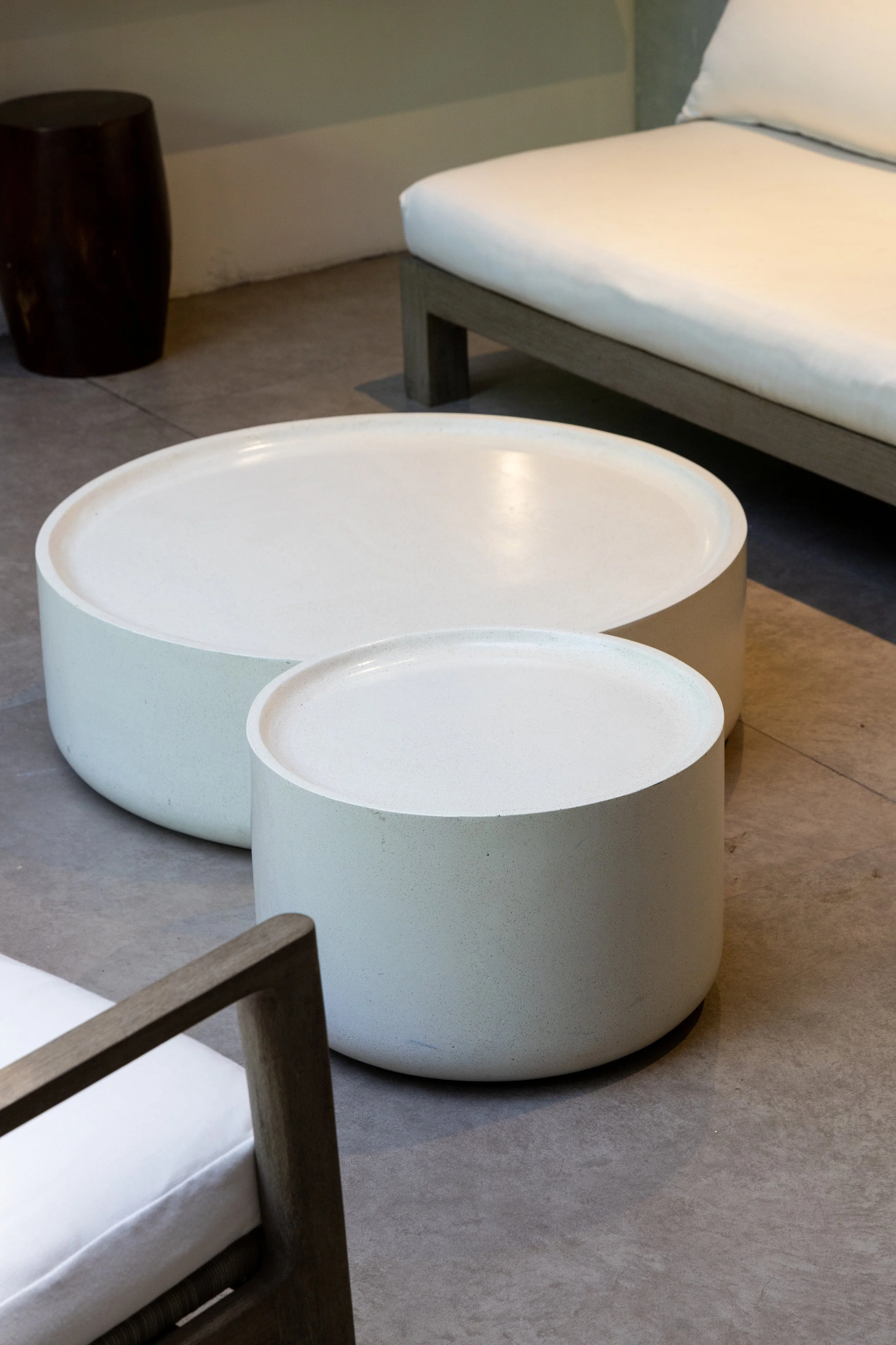 Two modern white concrete coffee tables of different sizes in a minimalist living room.