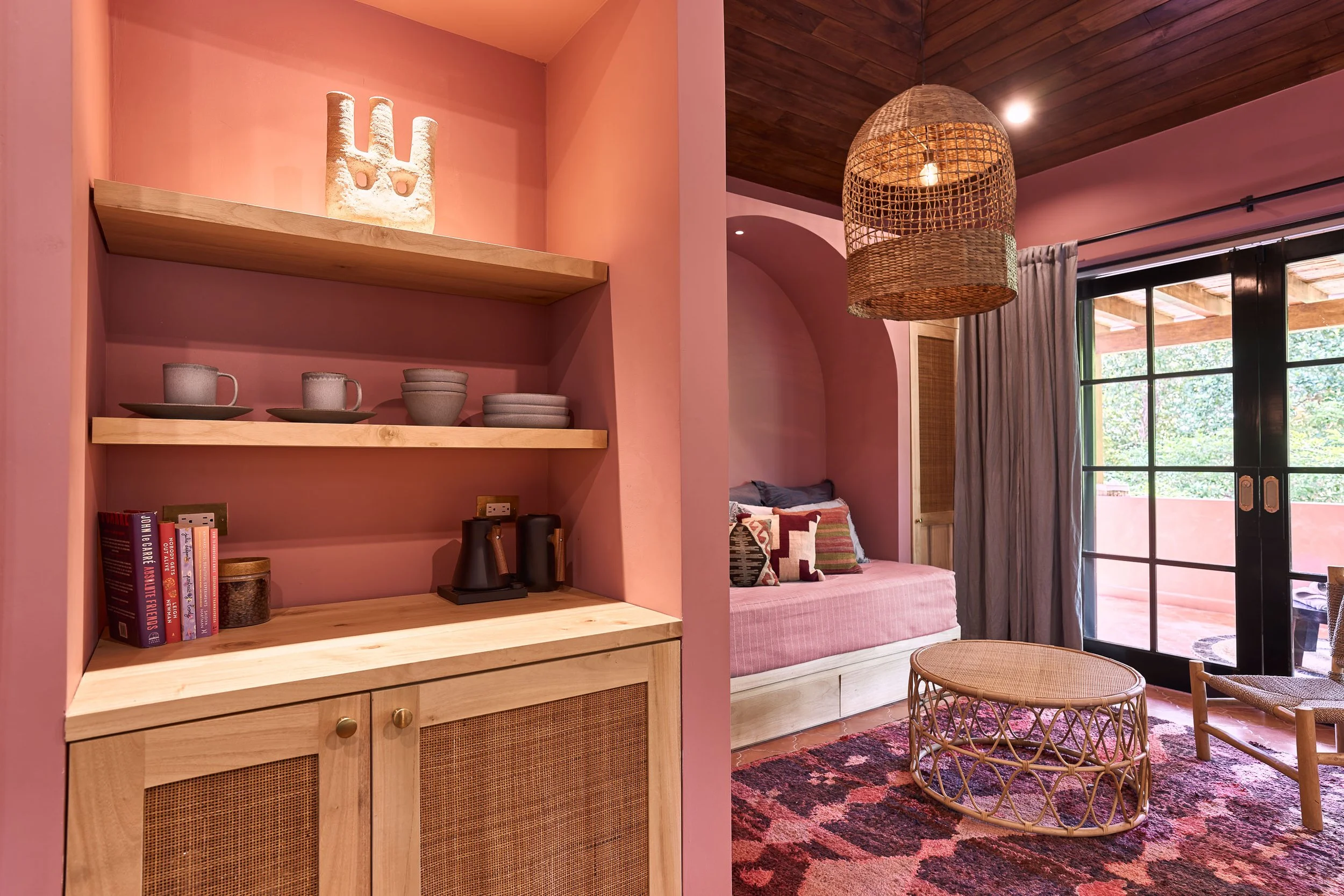 Coral-pink reading nook with built-in oak shelving, a daybed and a rattan pendant, Casa Ladera Nosara