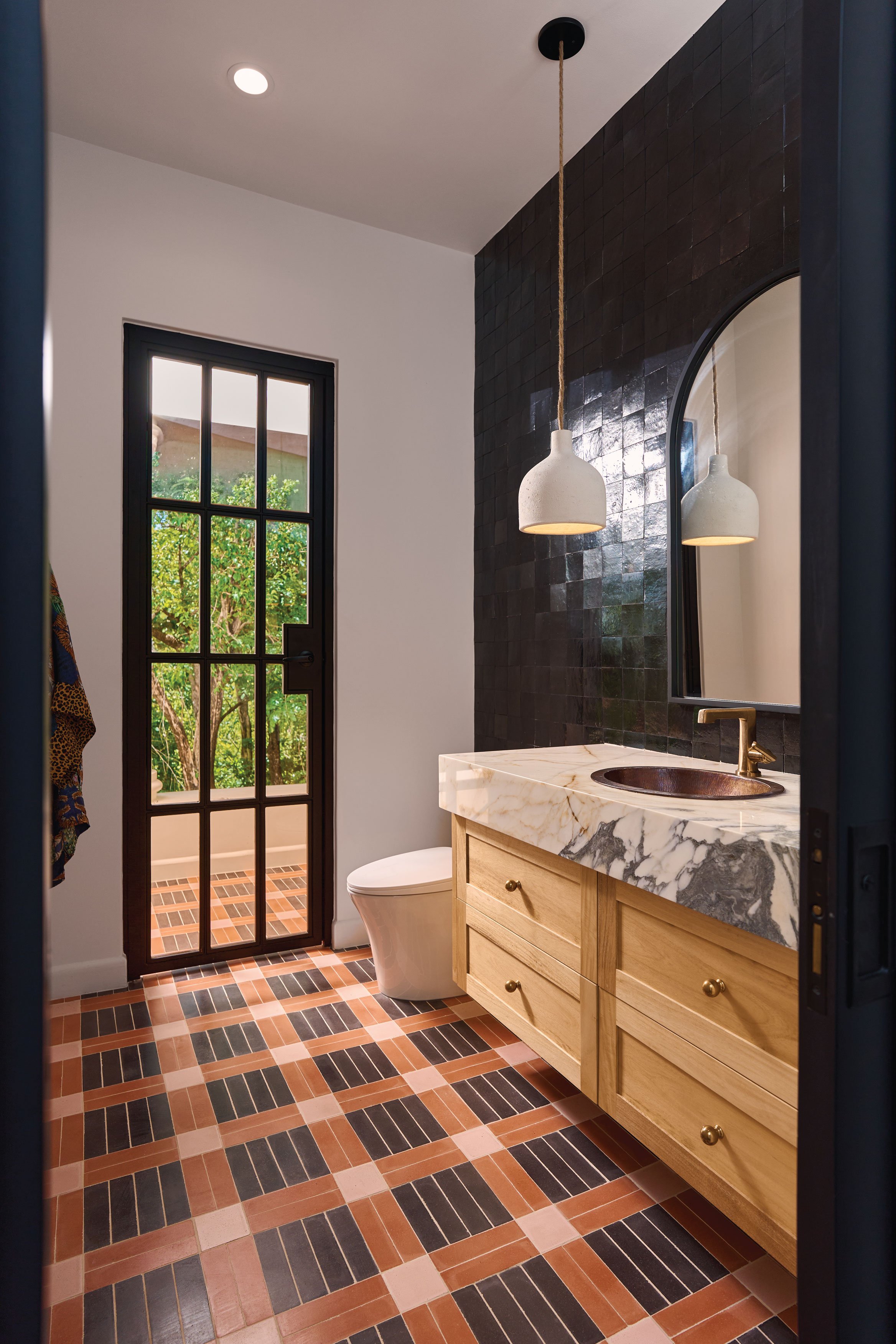 Patterned floor in terracotta, pink and black tiles beside an oak vanity, Casa Ladera