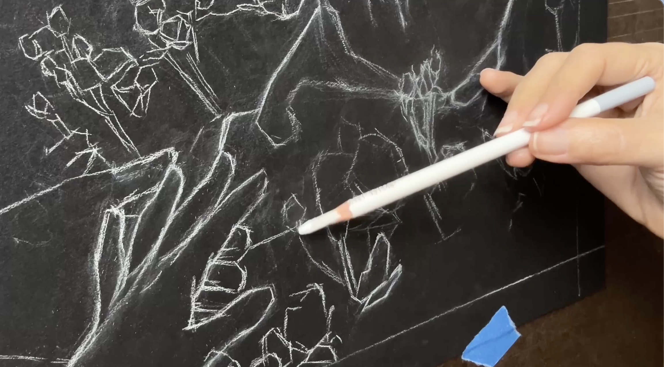 Photo of an artist drawing hands and flowers on black paper using pastel