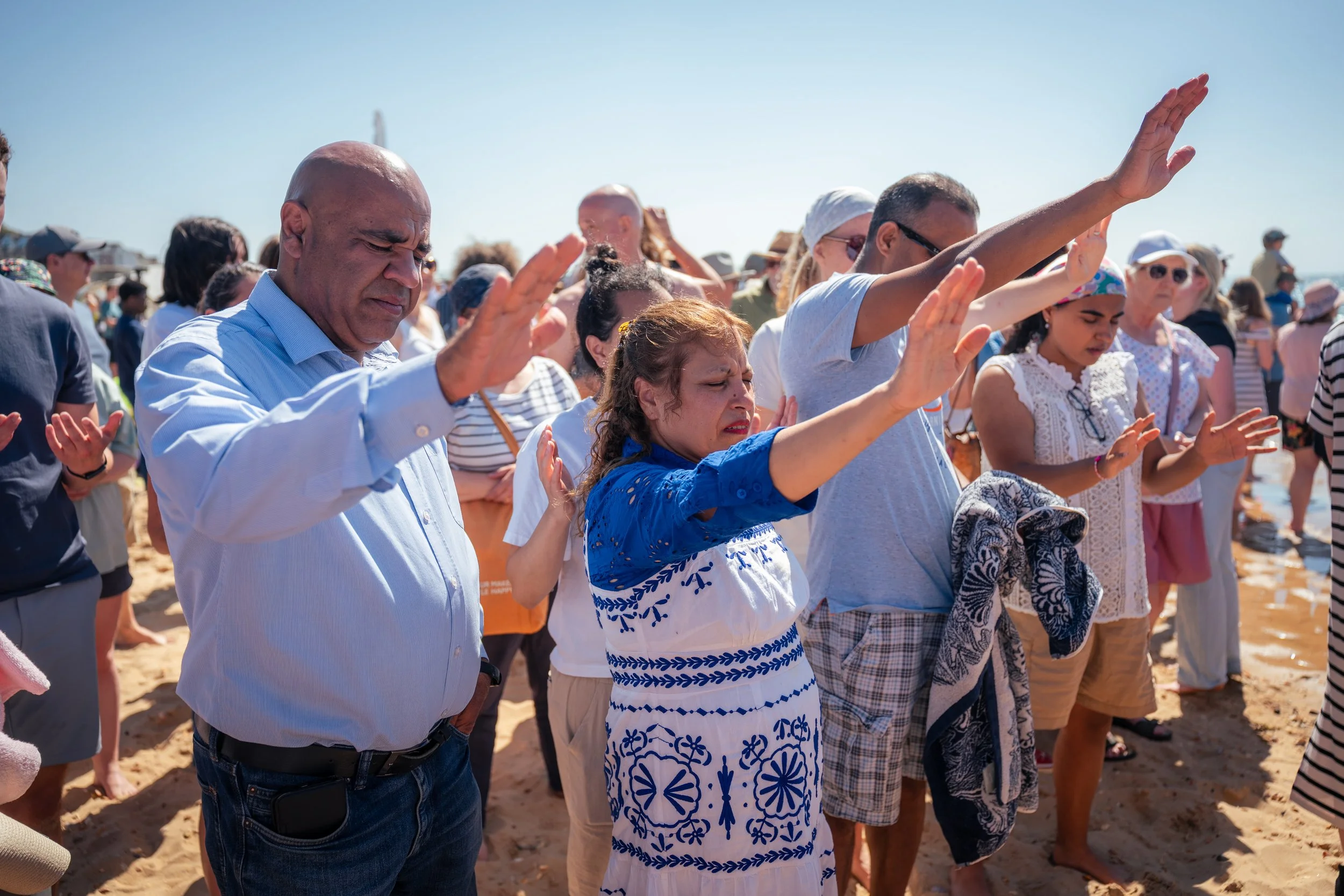Men and women praying at the beach