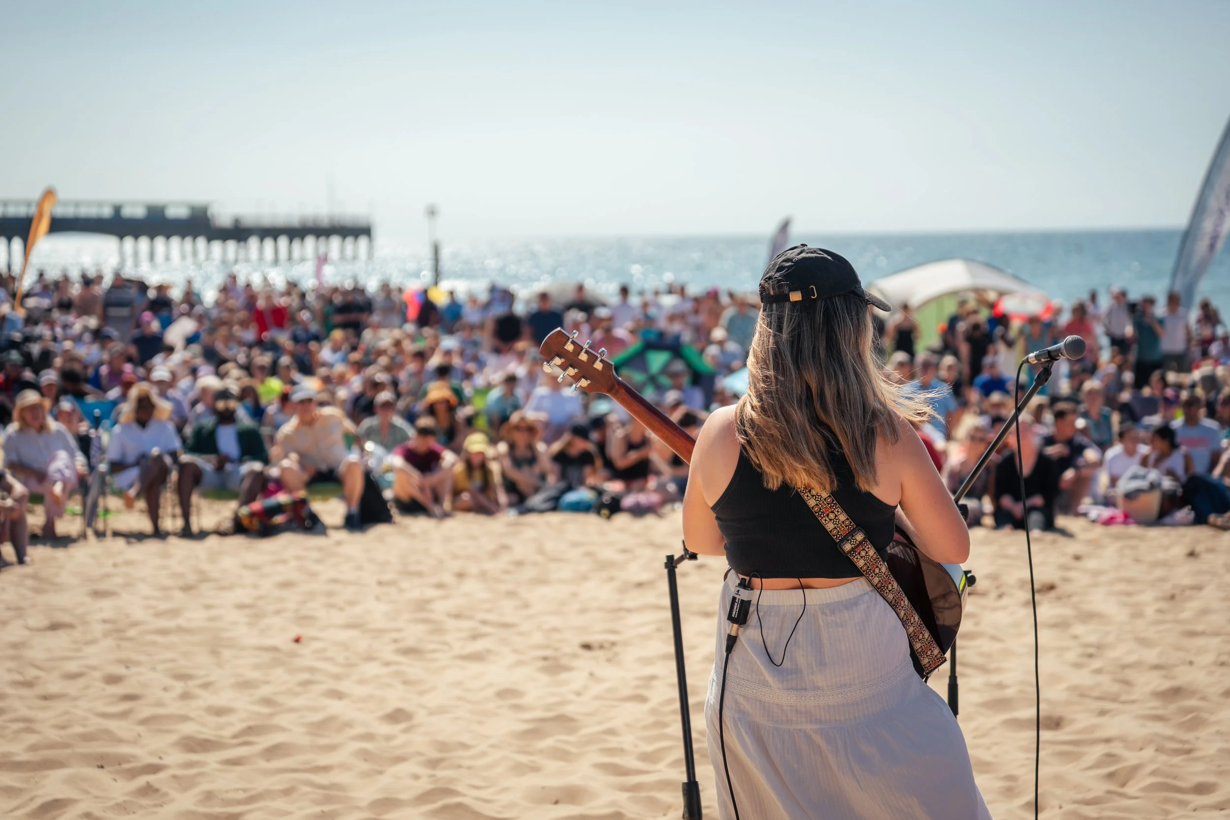 A singer at a beach baptism facing a large crowd