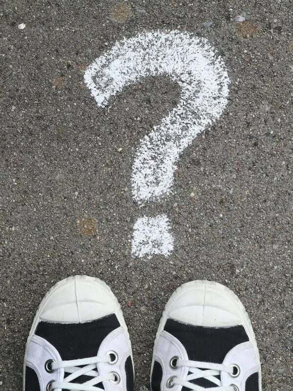Sneakers standing on question mark. Symbolizing confusion, needing clarity and direction, seeking support from online therapist in Texas, providing counseling for women who want to heal from financial trauma, perfectionism, burnout, guilt, or anxiety