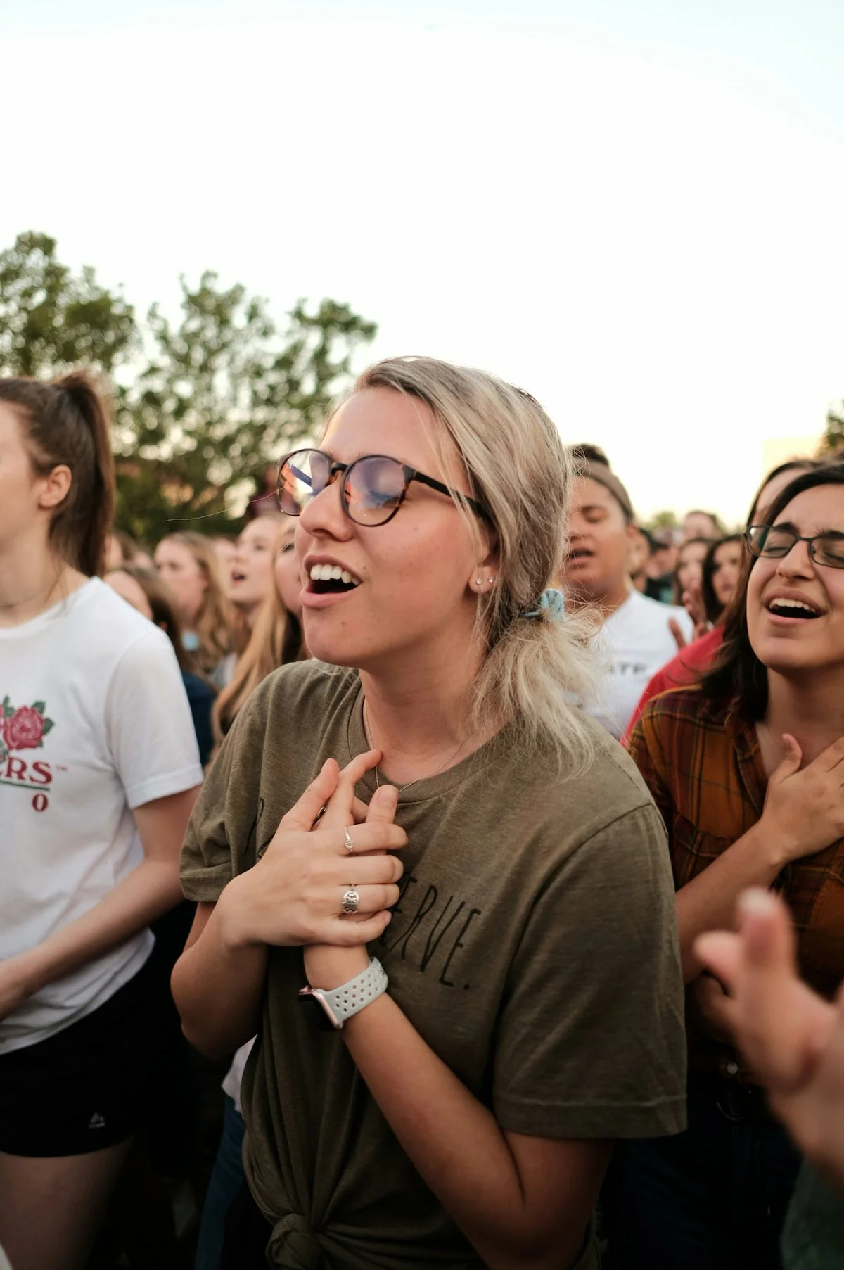 Woman singing with hand over heart at a concert. Symbolizing embodied connection, emotional resonance, and belonging, available through online therapy for women by culturally responsive Latina therapist in Houston, Texas.