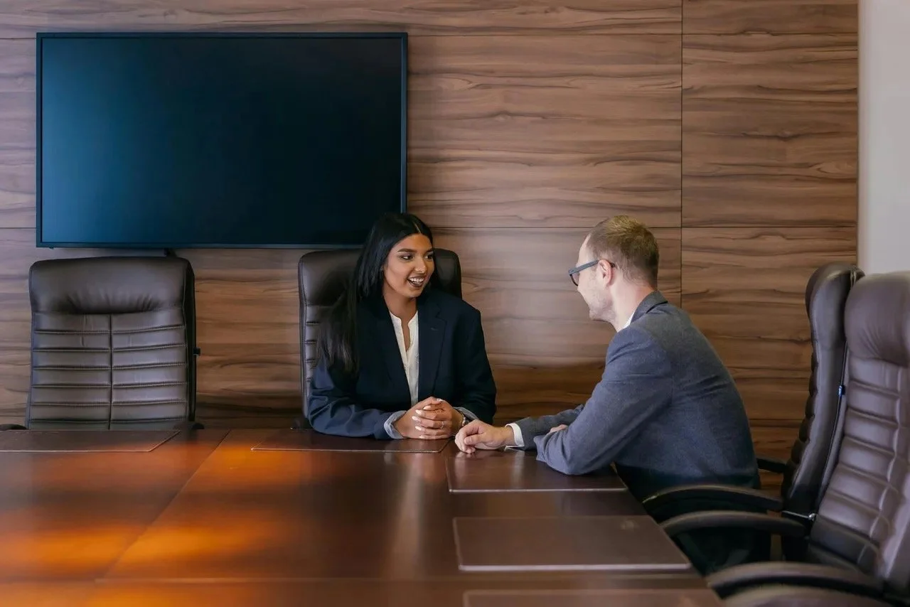 Woman of color speaking with Caucasian man in conference room