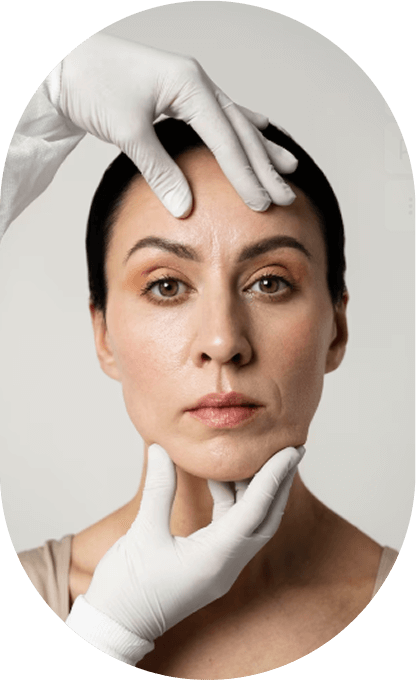A woman with a neutral expression having her face examined by a person wearing white gloves.