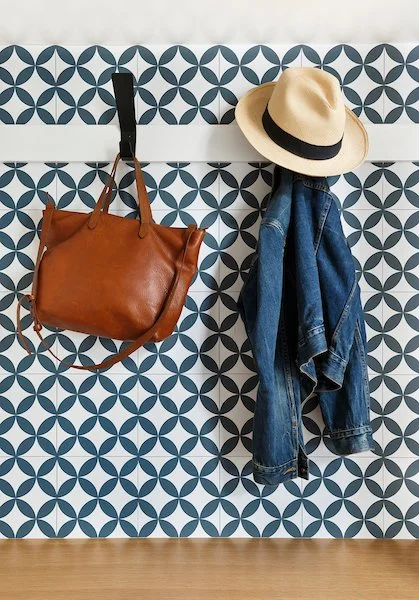 Hat, denim jacket, and brown leather bag hanging on a patterned wall.