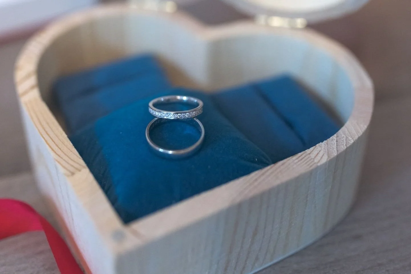 Une boîte en bois contenant deux alliances, une avec des pierres précieuses, posée sur un coussin bleu