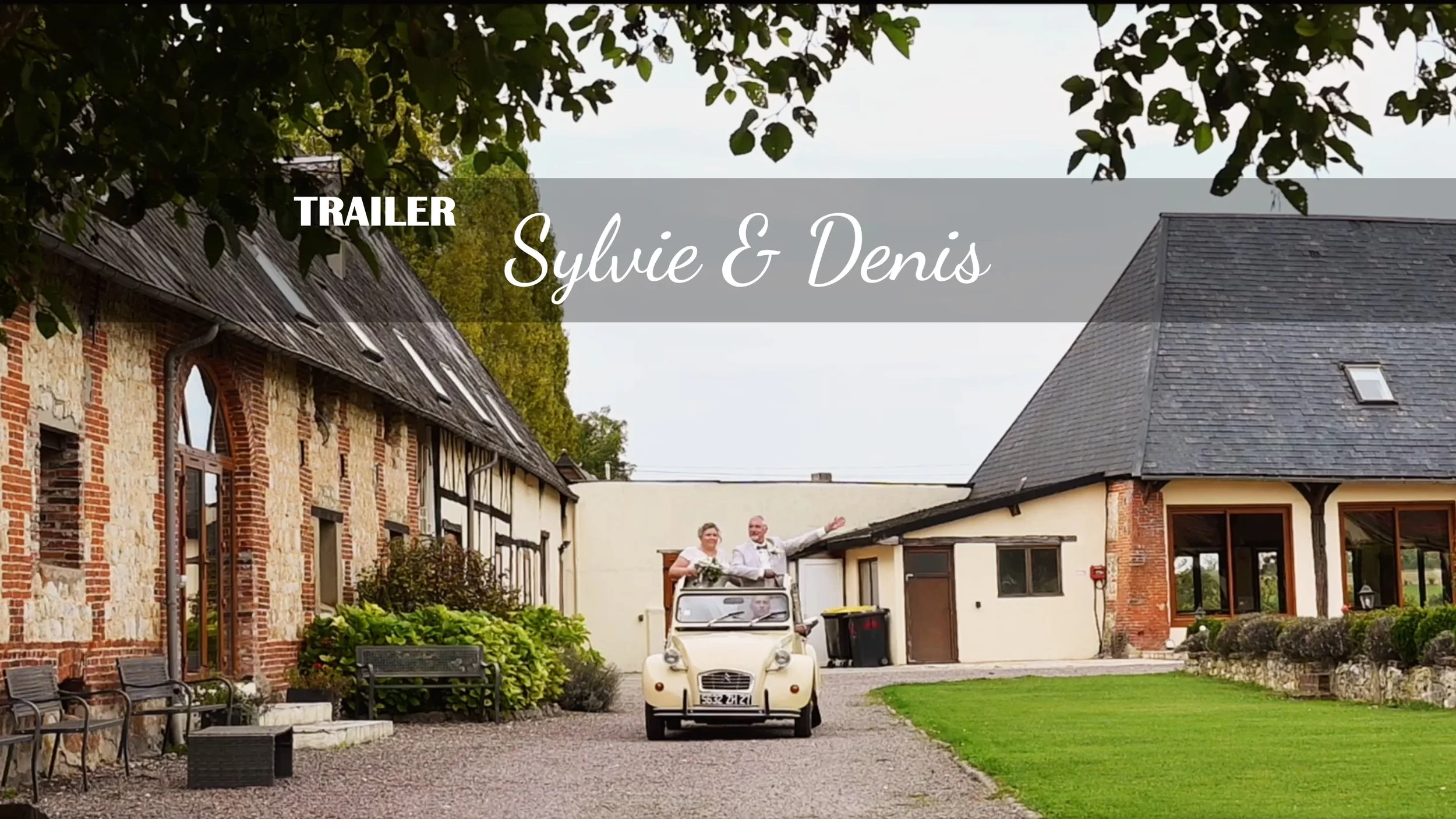 Un couple de mariés souriants à bord d'un véhicule électrique blanc, allant vers une ferme ou un lieu de mariage avec des bâtiments en pierre et en bois, entouré d'une végétation verdoyante.