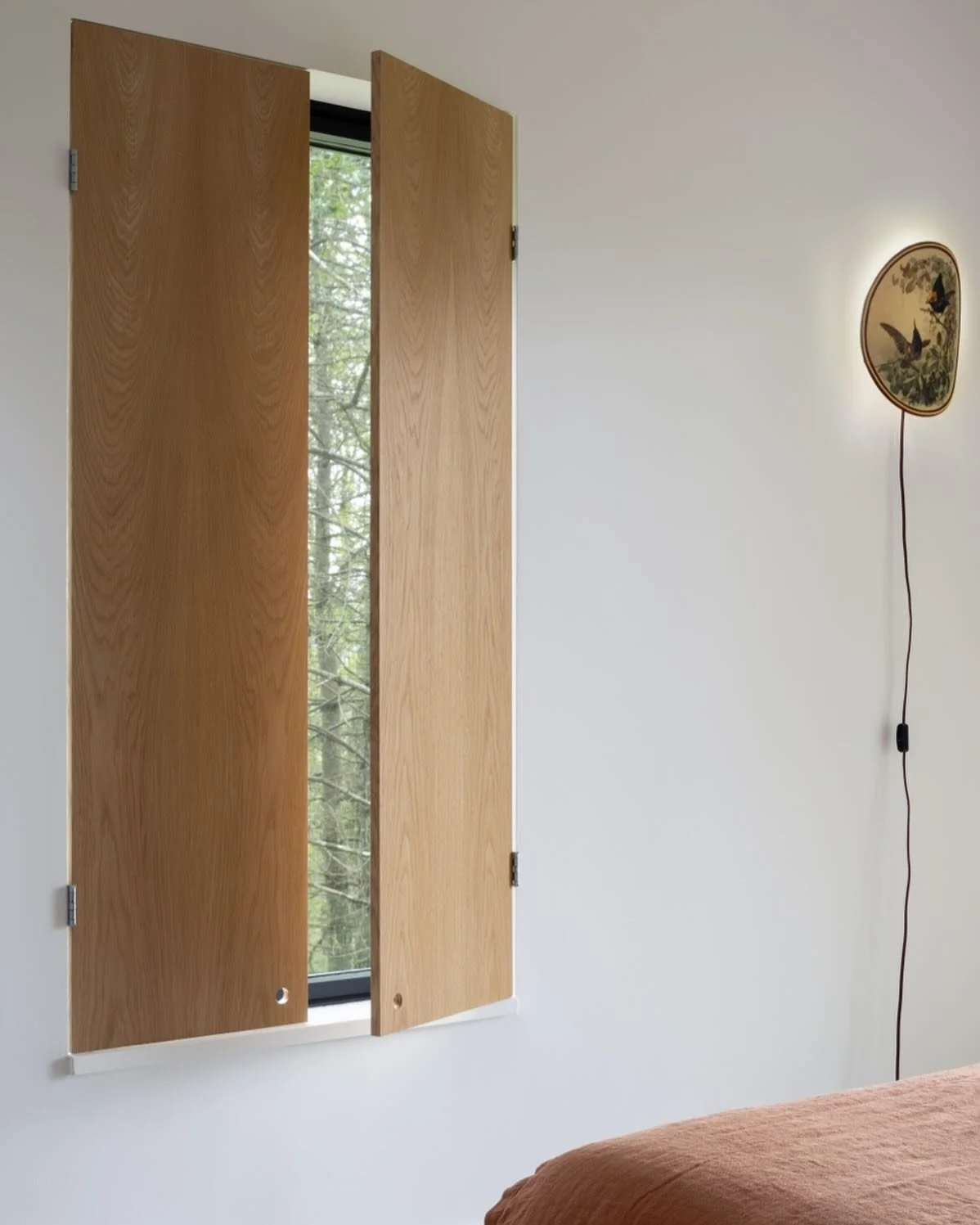 I often find the simplest solutions to be the most beautiful.  In this guest bedroom, finished plywood oak shutters are installed on utilitarian steel hinges.  They are a joy when open or closed.  Photo @devonbanksphoto