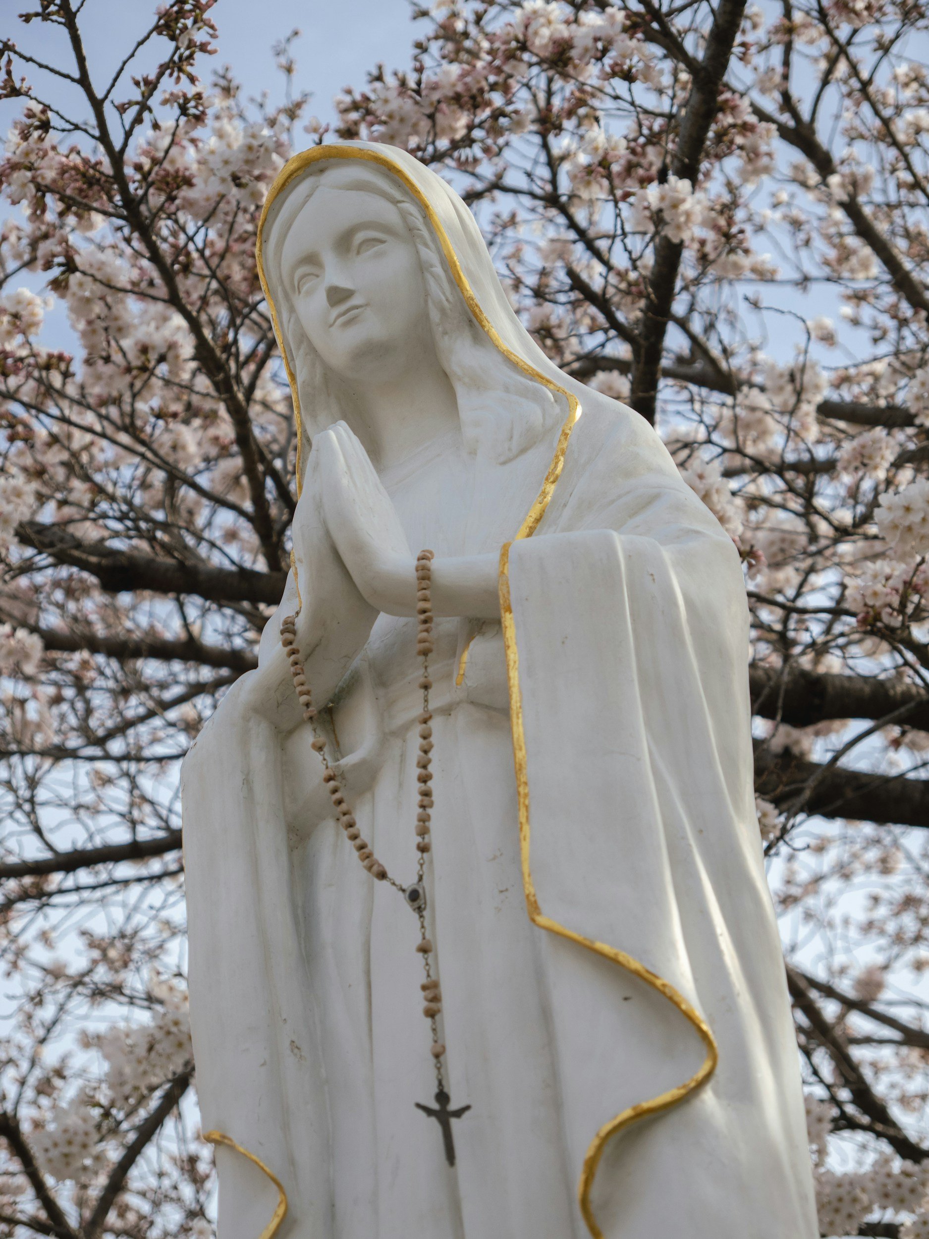 Statue of Our Lady of Fatima with rosary over her prayer folded hands.