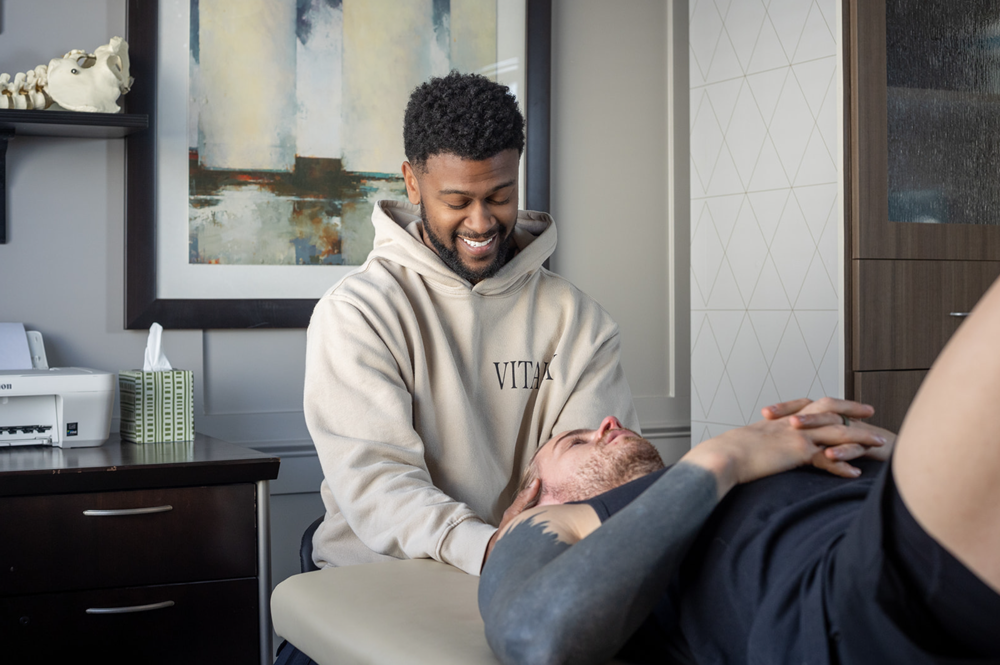 Physical therapist examining a patient's elbow in a clinical setting.