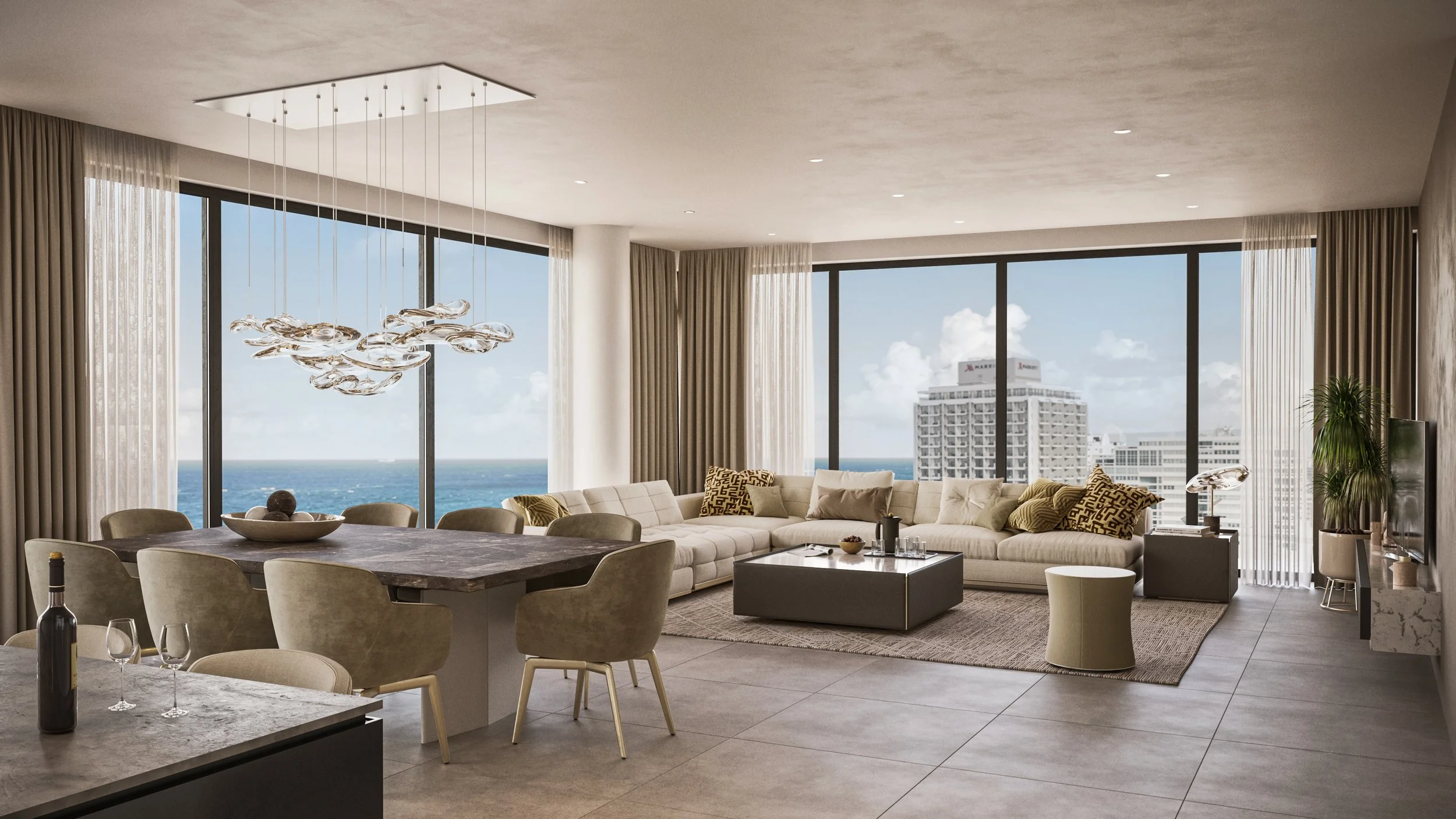Modern living room with large windows showing ocean view, white sectional sofa, coffee table, dining table with beige chairs, and contemporary chandelier.