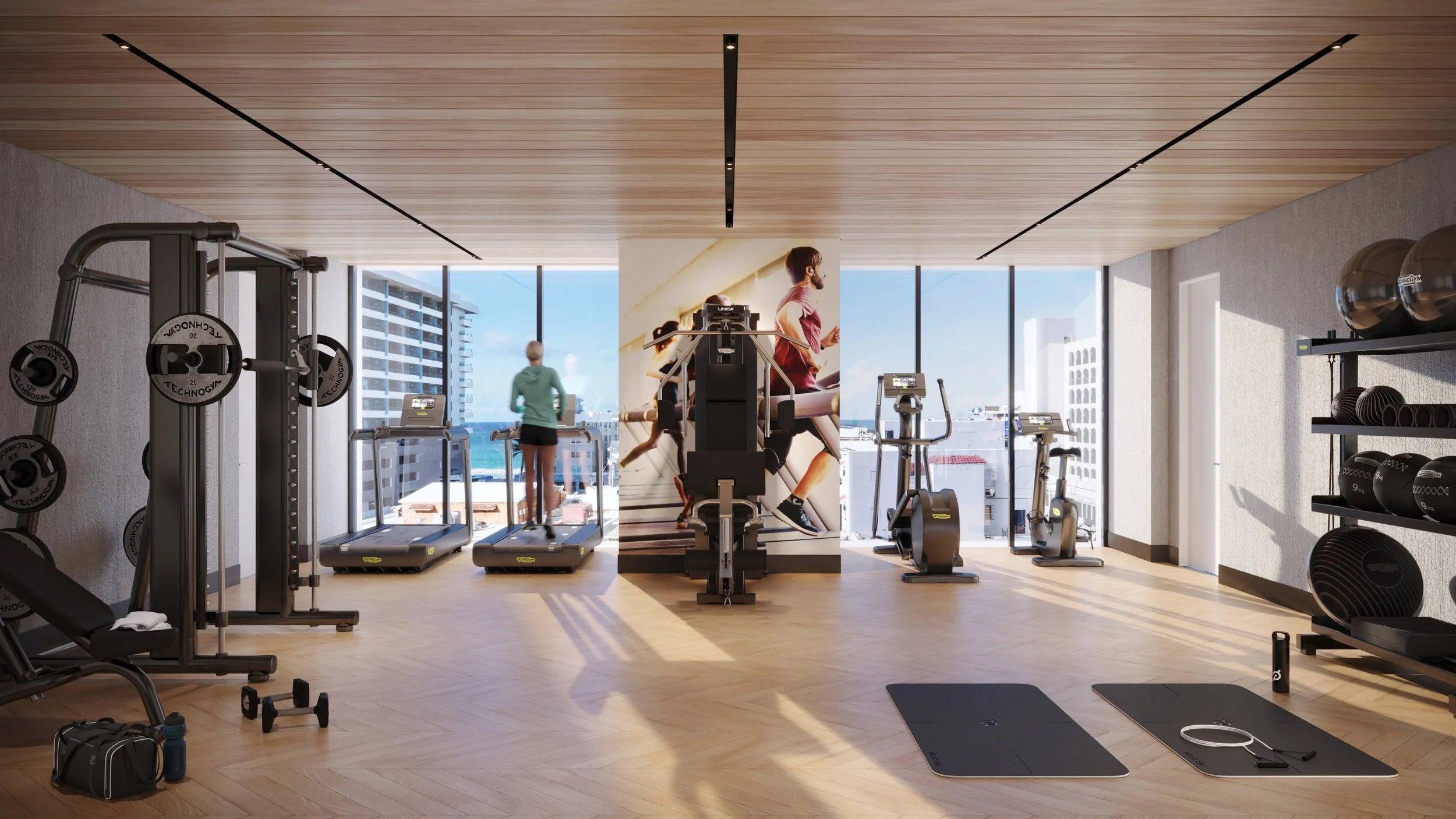 A modern gym with cardio equipment, weight rack, and exercise mats, overlooking city buildings and ocean through large windows.