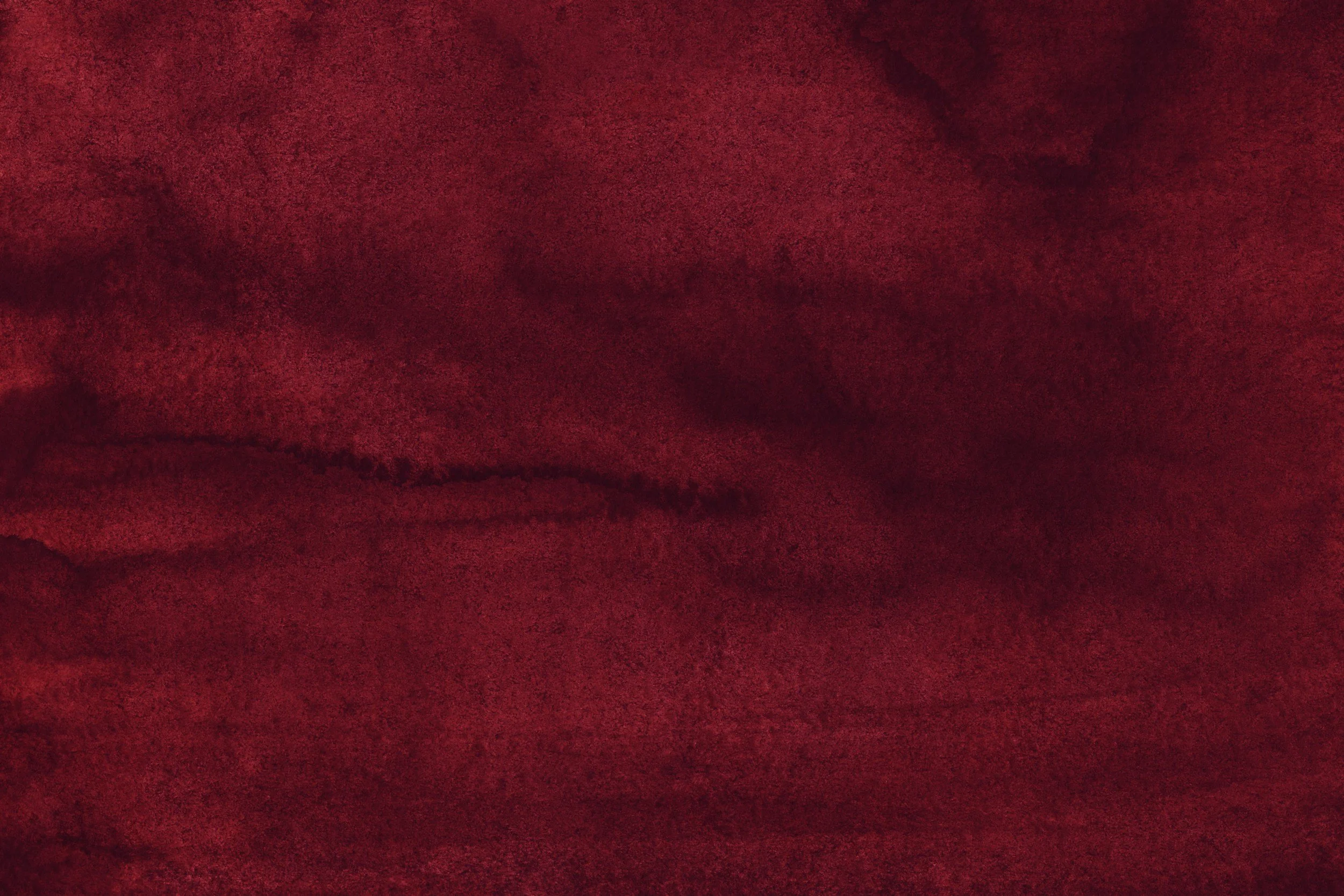 Close-up of a textured, deep red, velvet fabric with visible folds and creases.