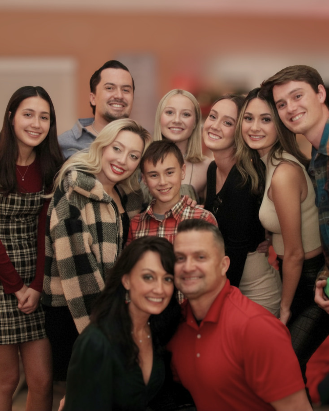 A group of twelve people posing together, smiling, at an indoor gathering or party.
