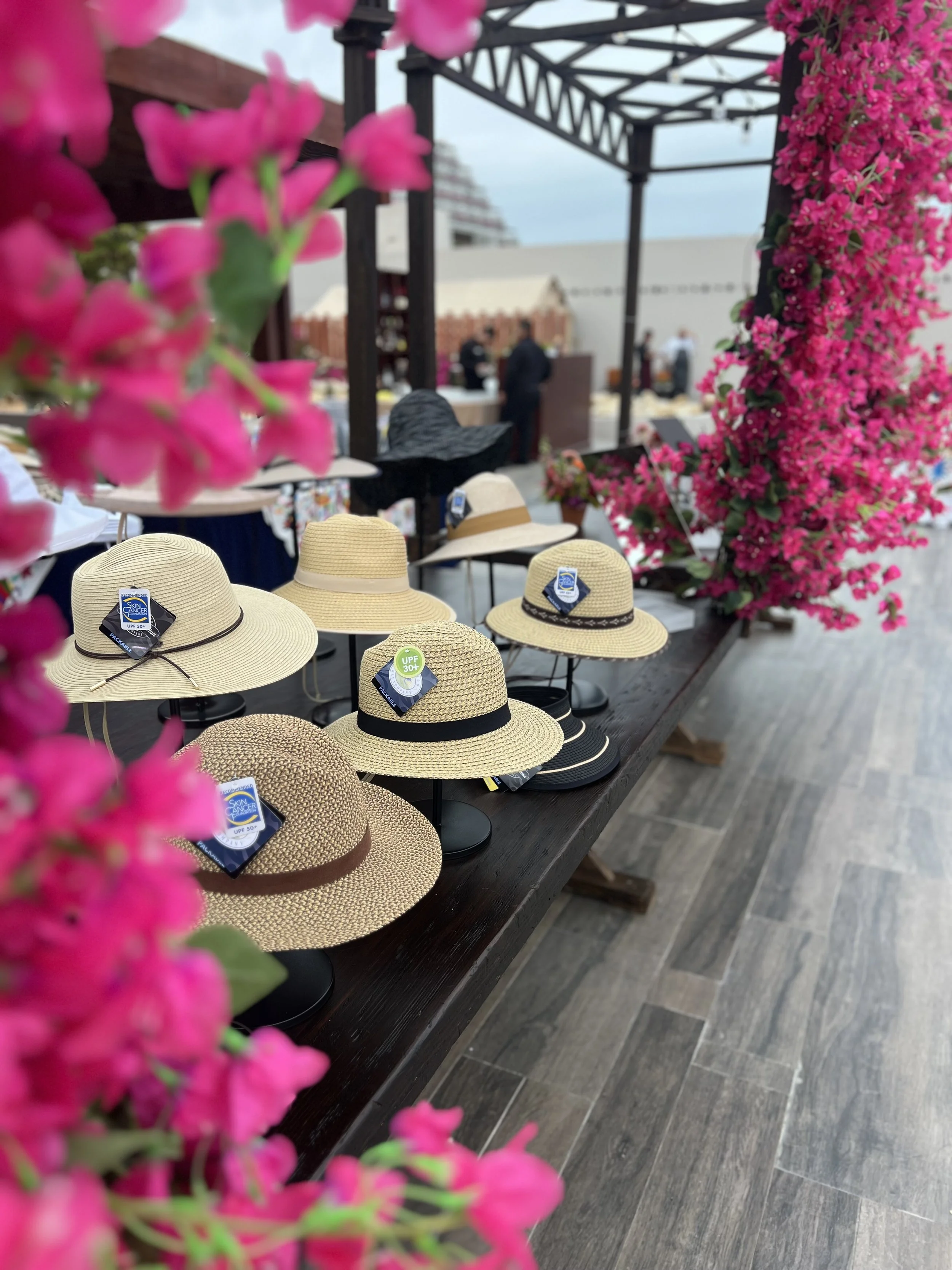 On-site corporate gifting suite featuring UPF sun hats on display, surrounded by bougainvillea — curated by Bluebird Gift Collective.
