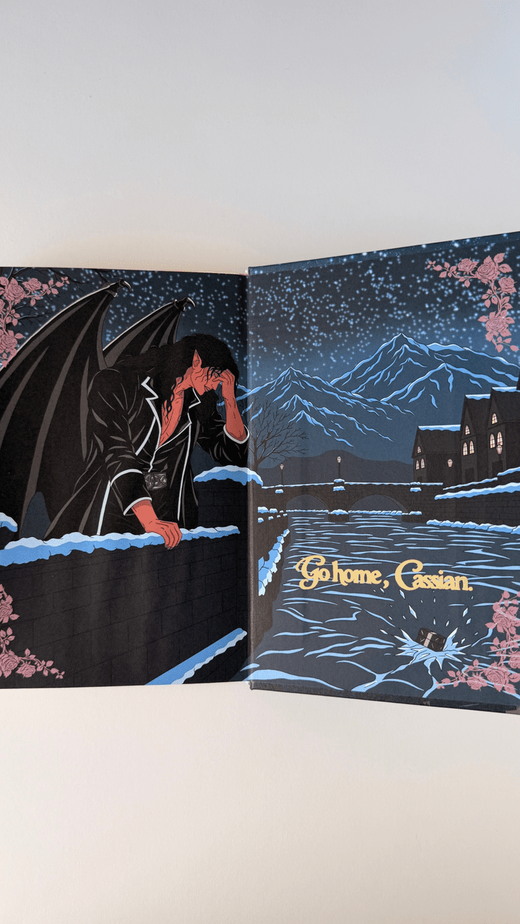 The book open at the back endpaper: Cassian at a snow-covered wall and Nesta’s gift breaking the ice on the river below, running across both boards.