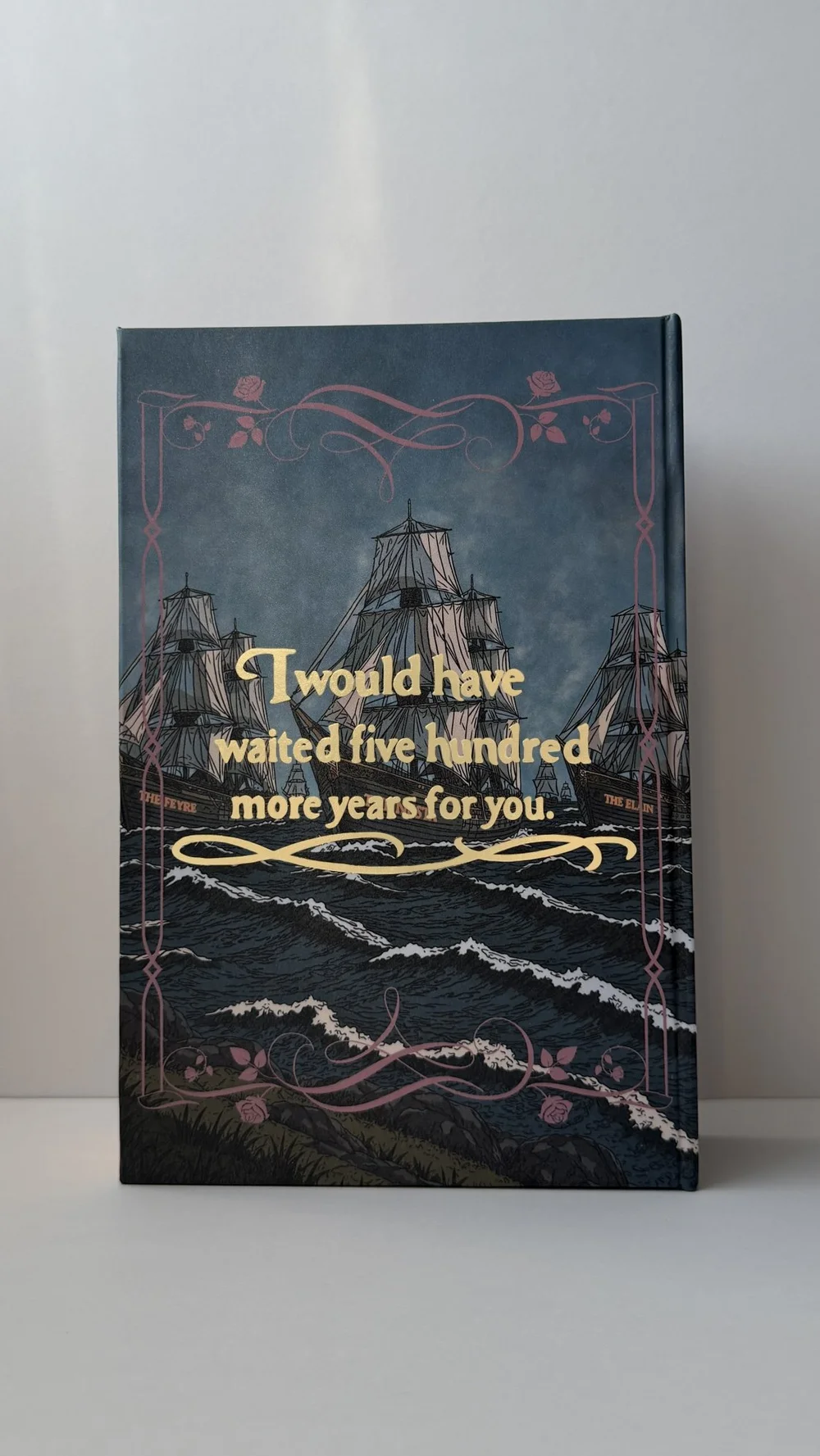 The back cover: an armada standing off a dark coast, with a foiled quote above the water.