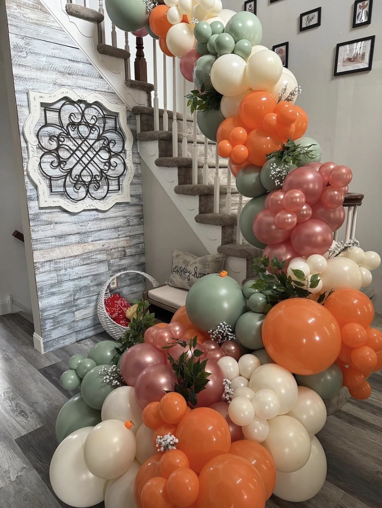 Custom balloon arch installation of red, orange, and green balloons tied and going up a home steps banister by The Design Ward for a bridal shower