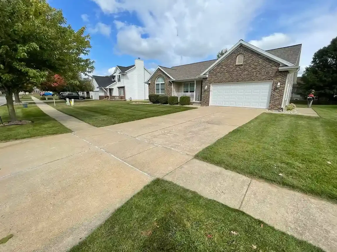 Freshly mowed suburban front yard with clean driveway edging in Michigan.