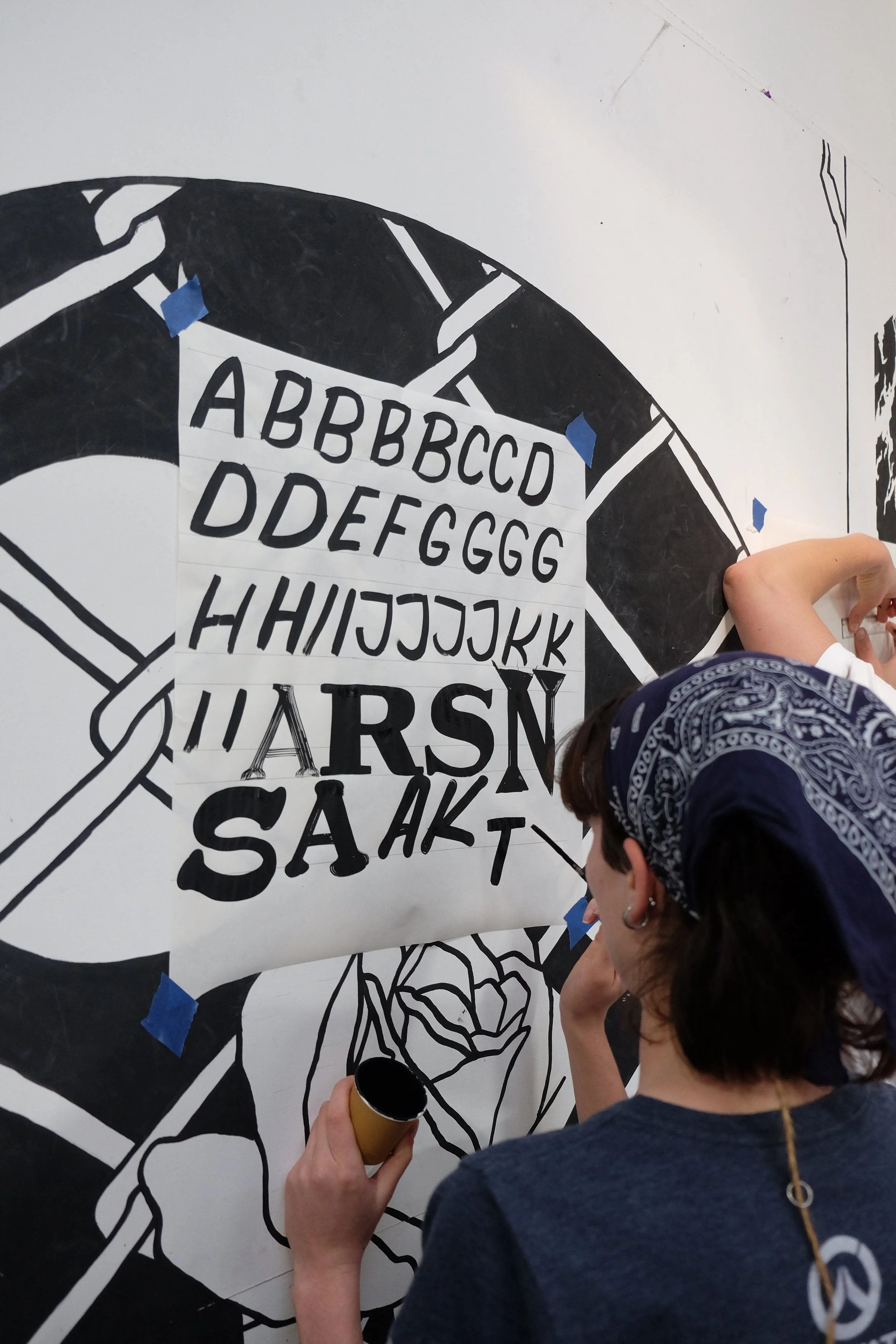 Person painting on a wall with stenciled letters