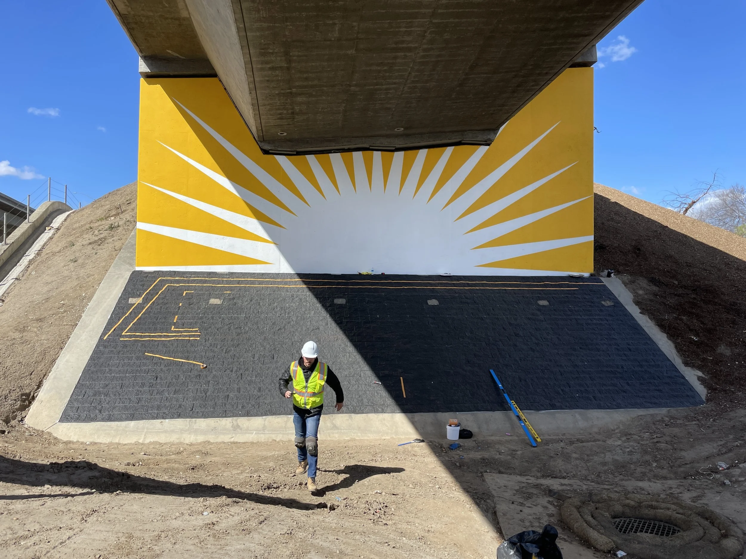 Gastón The Painter doing a mural under a bridge.