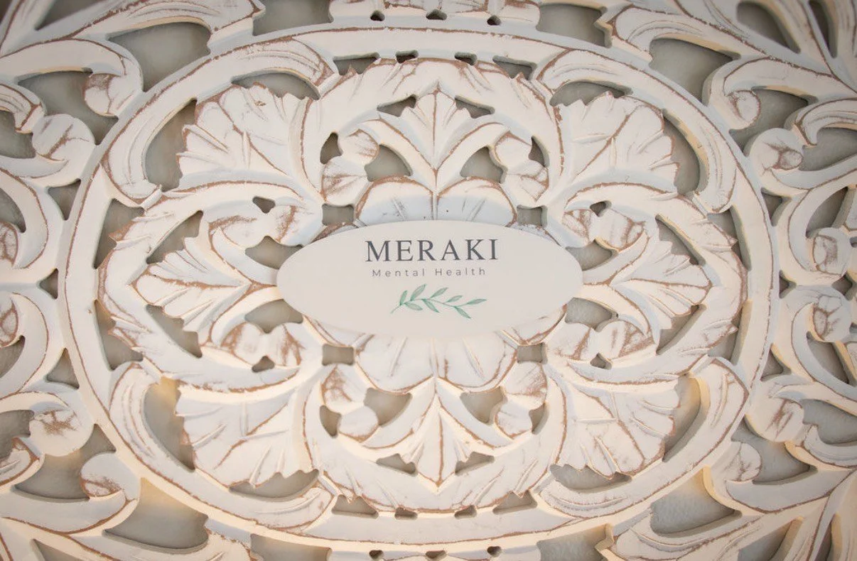 Intricate decorative design with a central label reading 'MERAKI Mental Health' and a small leaf illustration, surrounded by detailed carved patterns.