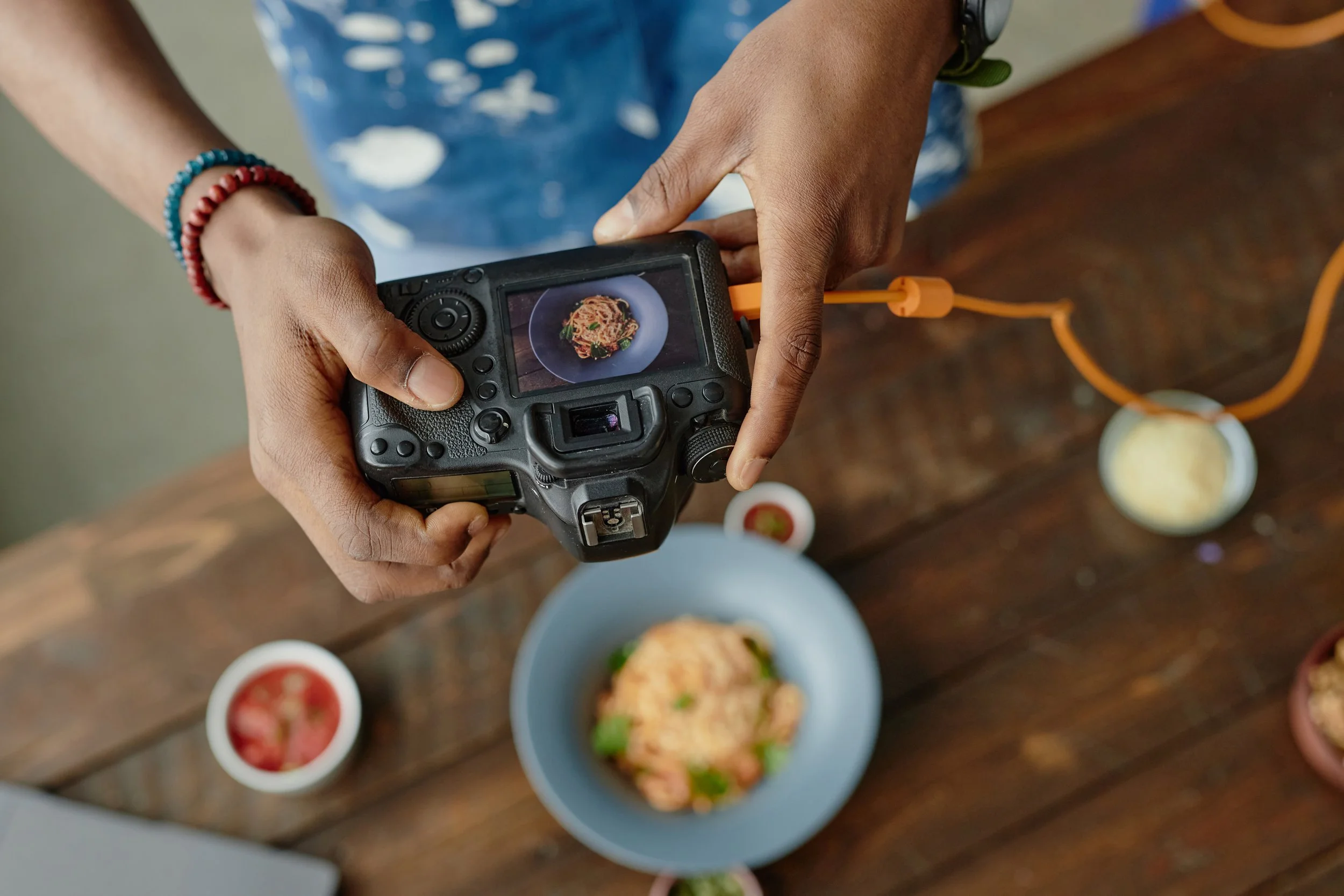 man taking a flat lay photo of food on a wooden table