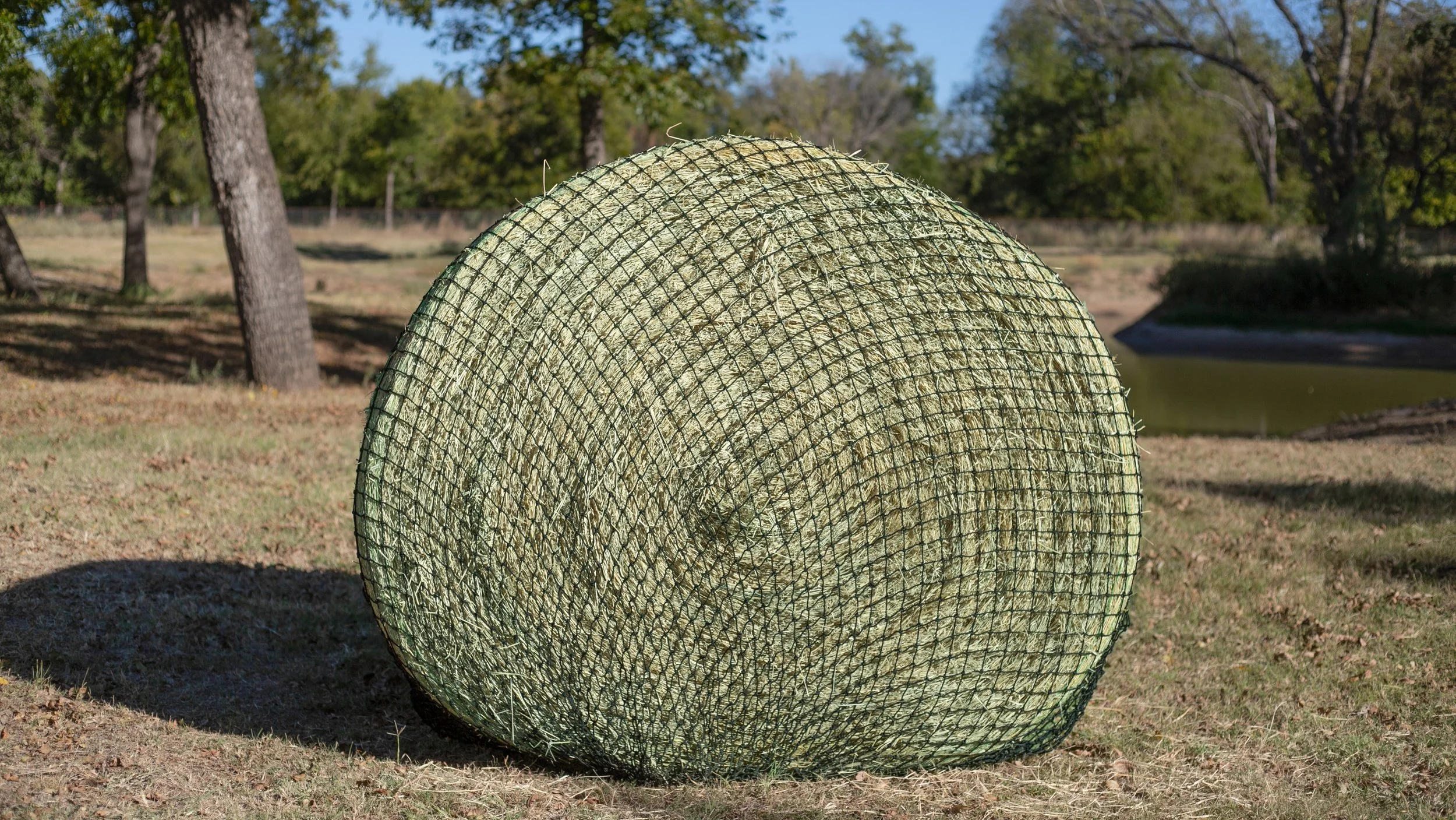Hay Chix large bale hay net wrapped around a round bale outdoors